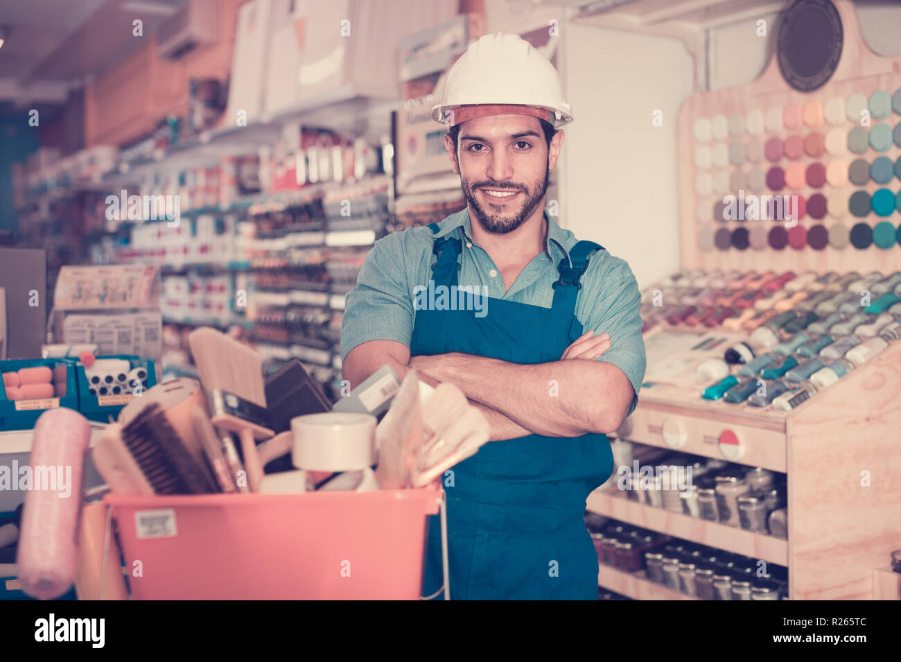 Happy cheerful positive smiling workman standing folded arms near