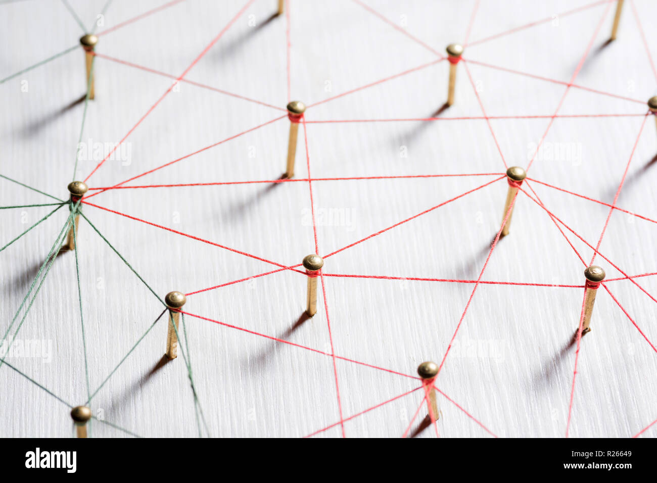 Linking entities. Network, networking, social media, internet communication abstract. A small network connected to a larger network. Web of gold wires on white wooden background. Network hub or key person. Stock Photo