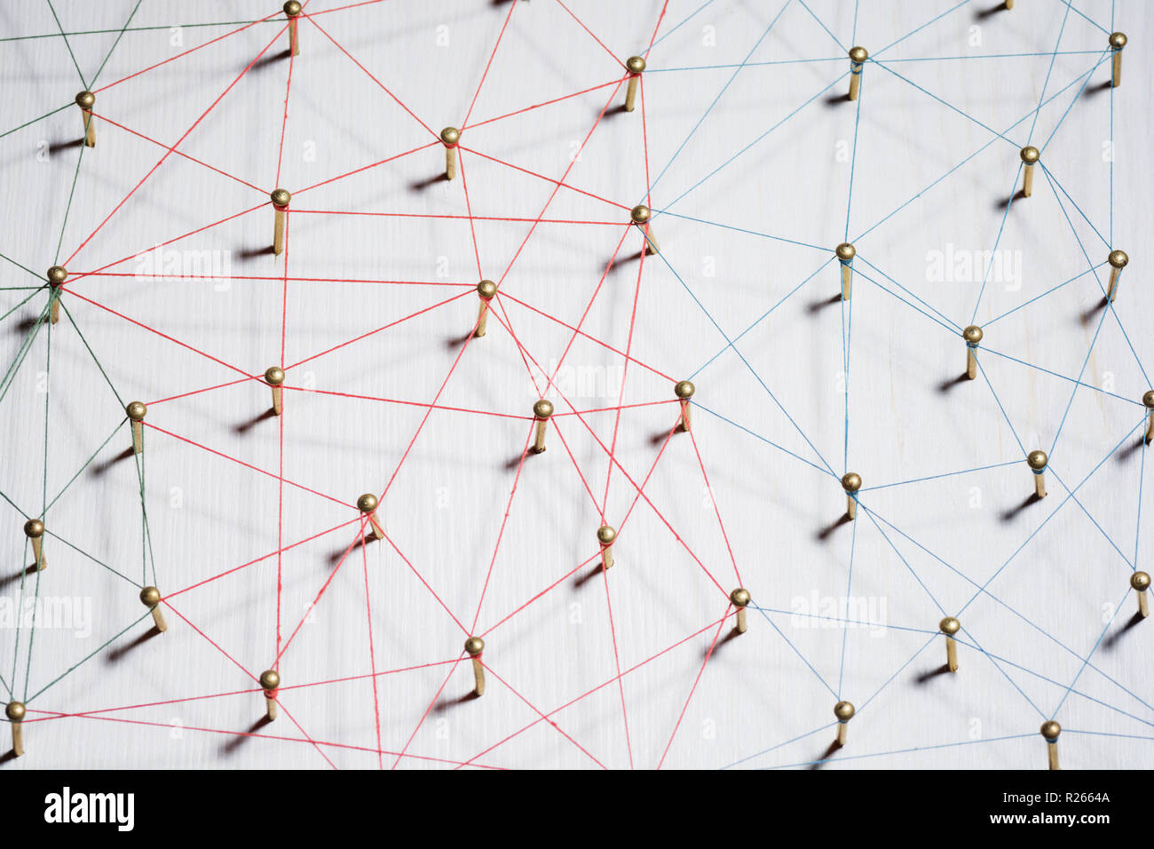 Linking entities. Network, networking, social media, internet communication abstract. A small network connected to a larger network. Web of gold wires on white wooden background. Network hub or key person. Stock Photo