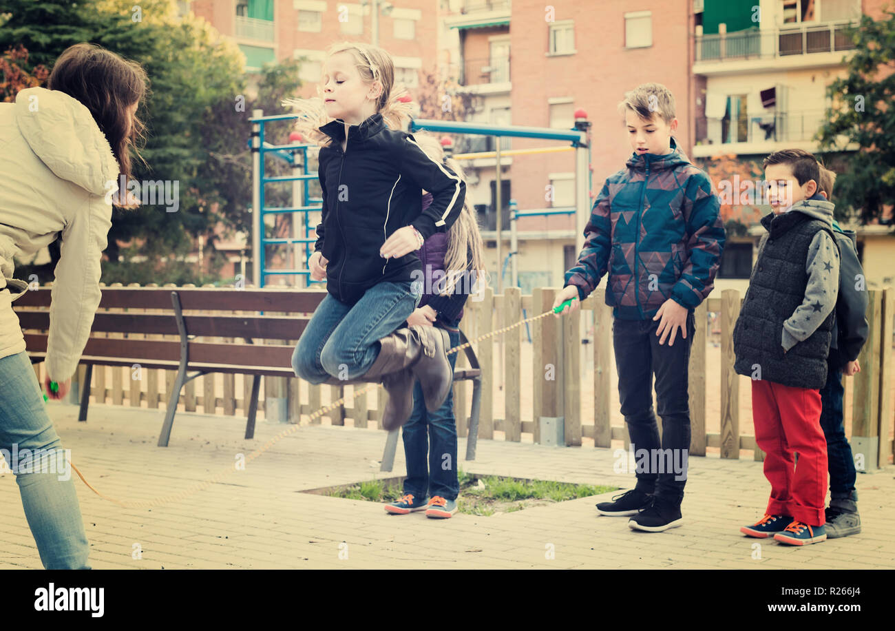 russian children playing rubber band jumping game and laughing outdoors