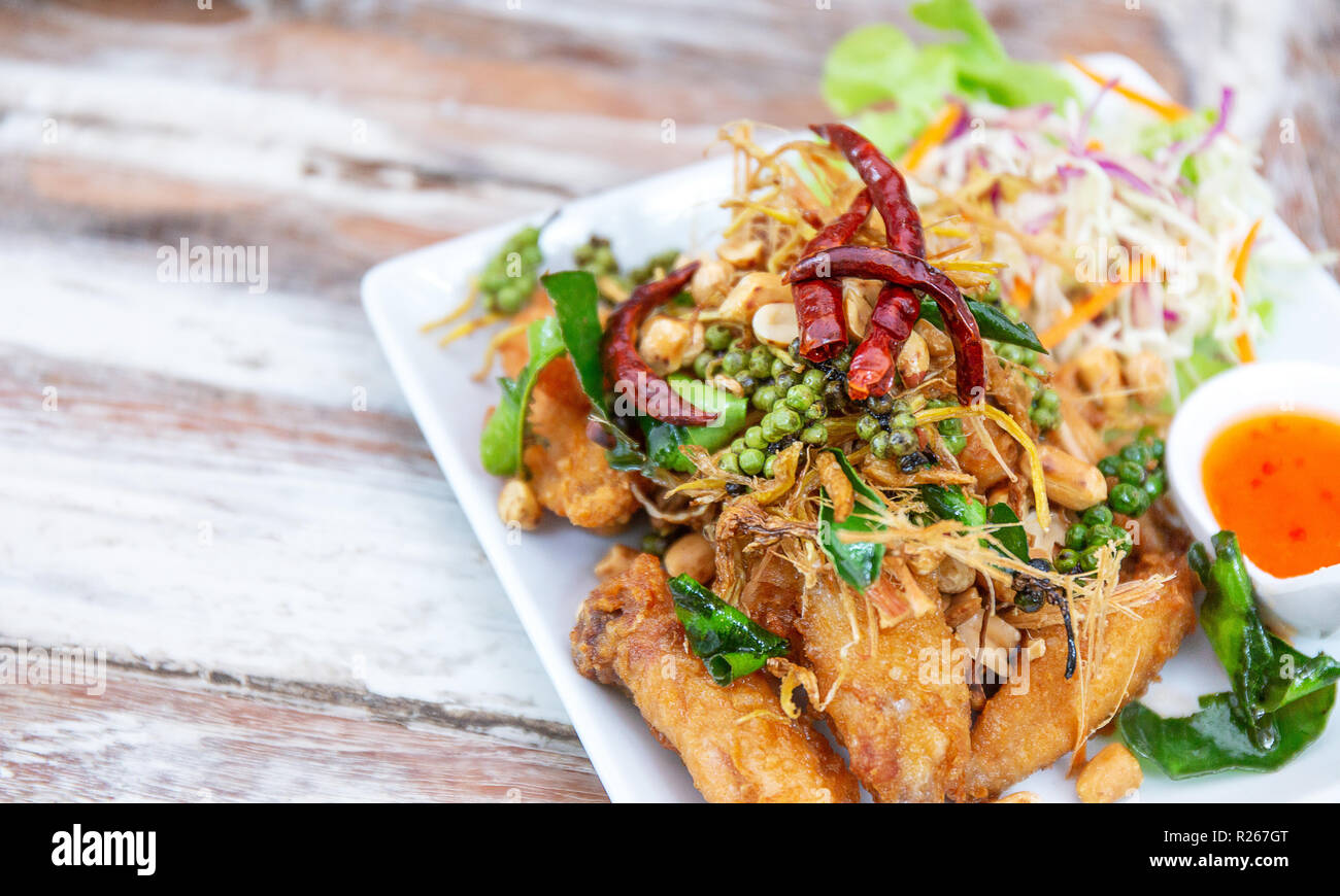 Yummy, delicious, fried wing chicken with herb, pepper, chilli, salad, and sauce, famous thai or asian food, on table in restaurant Stock Photo