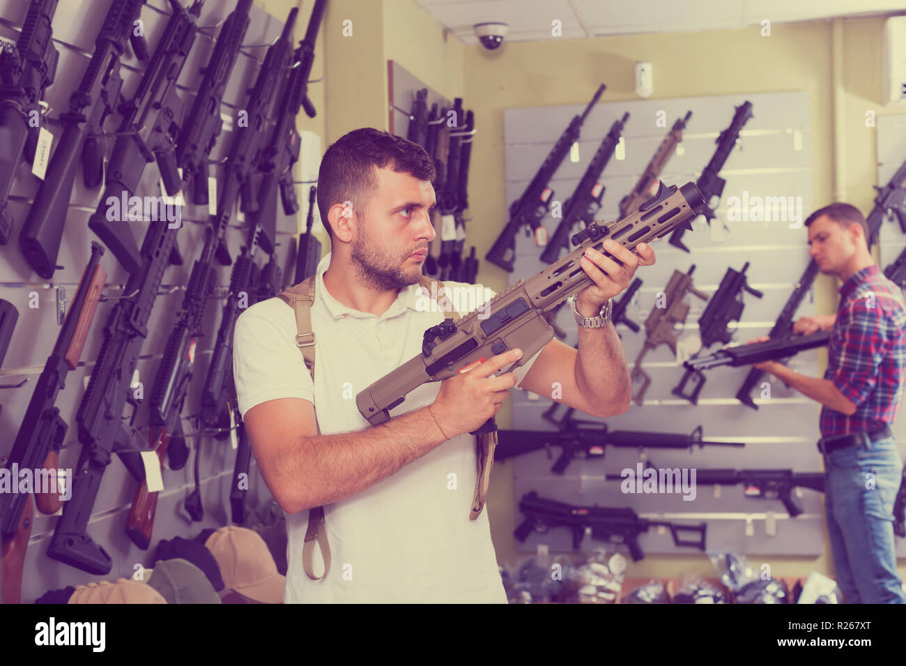 Two young men selecting air weapon in military shop Stock Photo - Alamy