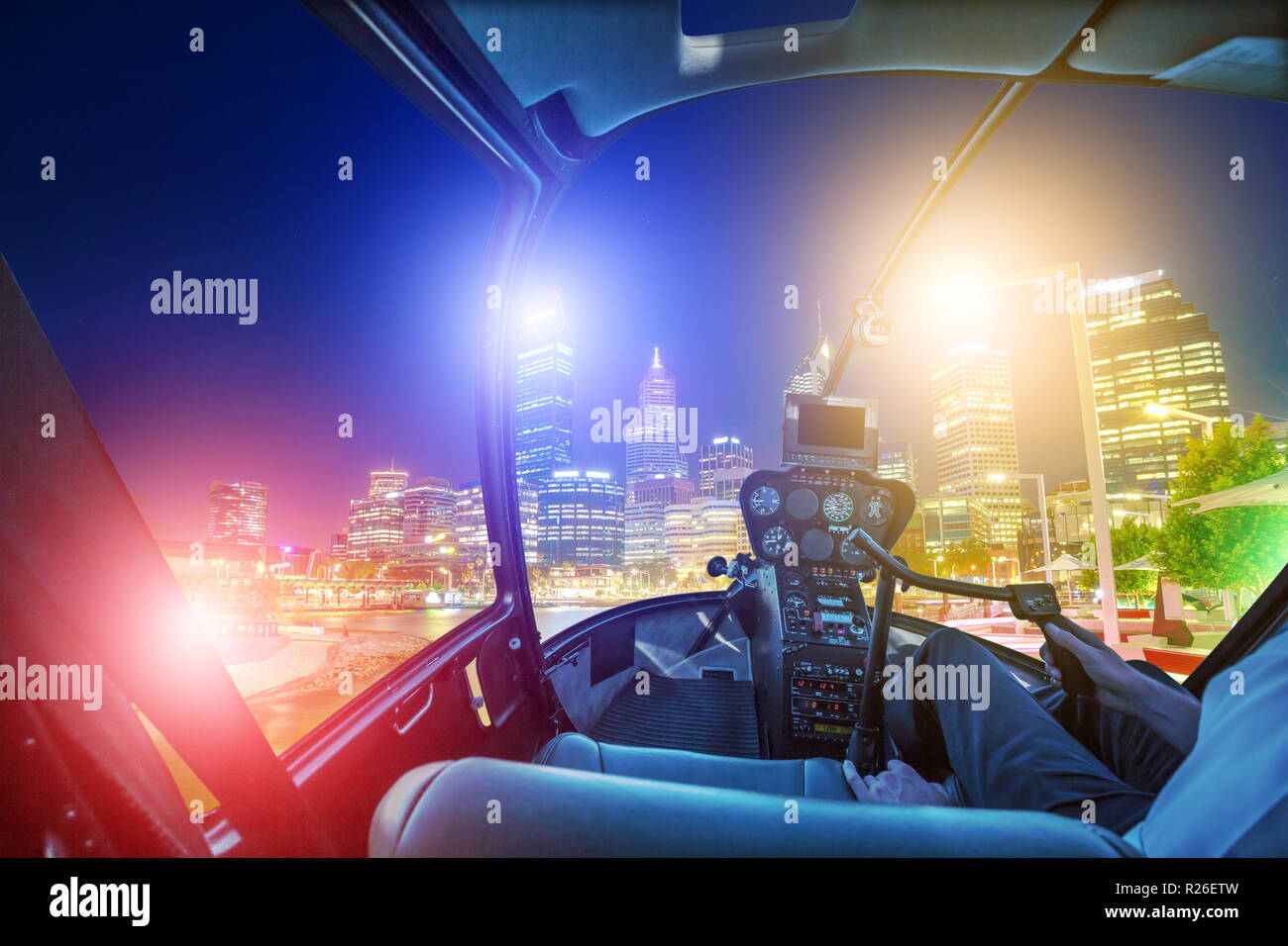 Helicopter cockpit interior flying on Perth city skyline lights. Scenic