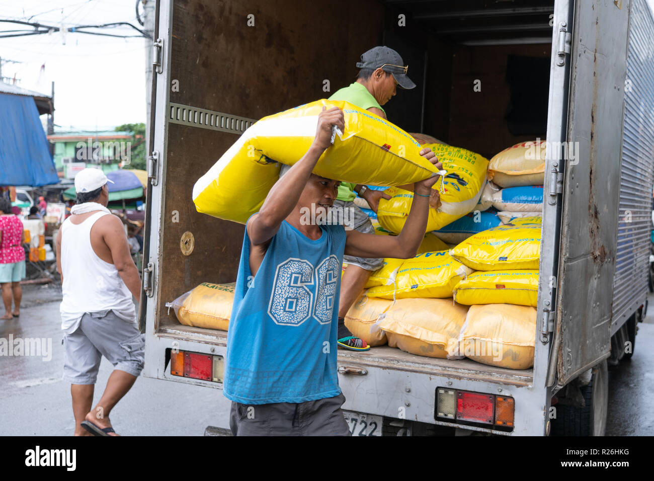 Concept image of rice usage within the Philippines,a man carrying a large 50kg sack of rice from