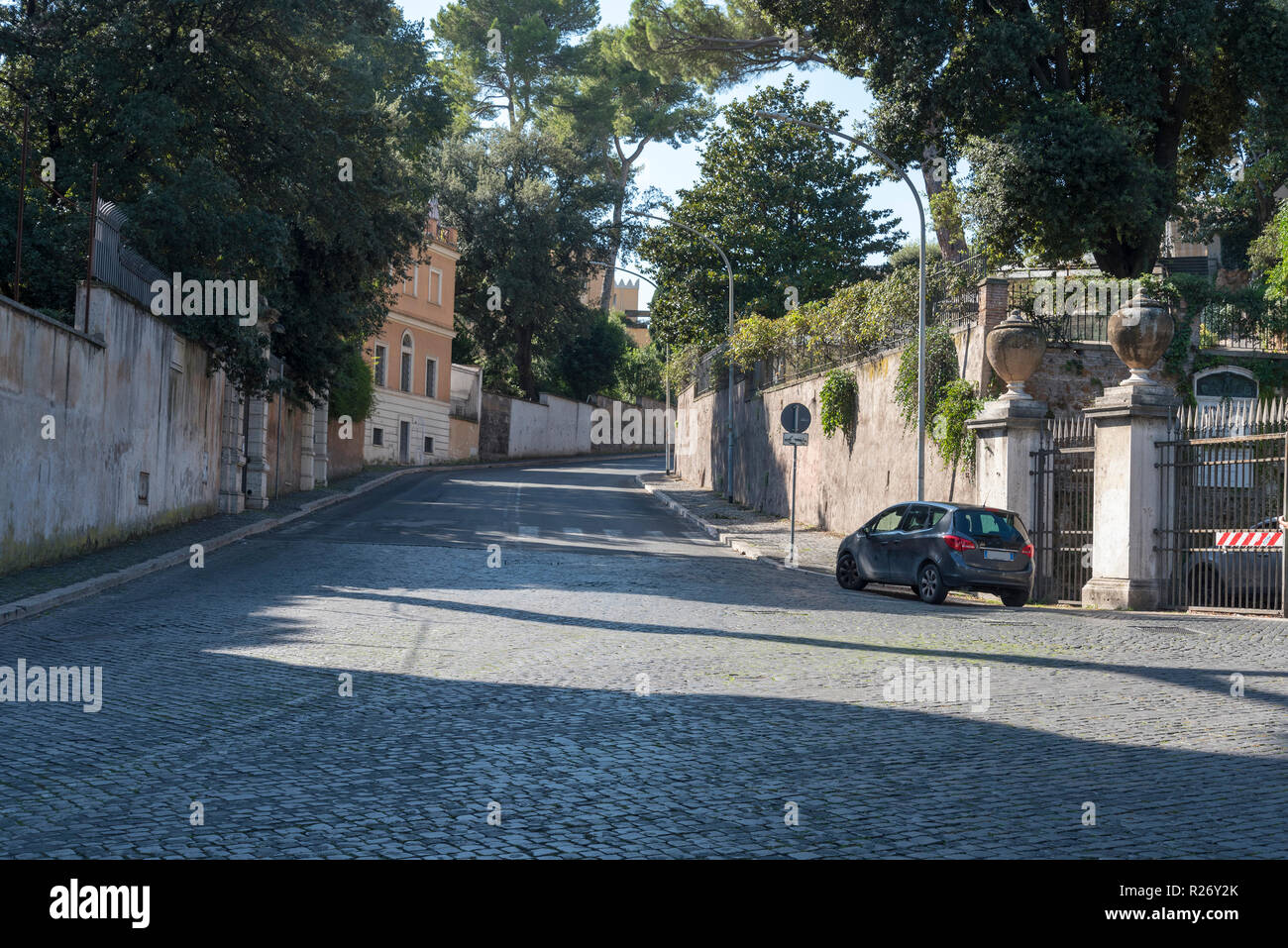 Road, home car in Rome on a summer day. The road from the pavers goes up the hill.