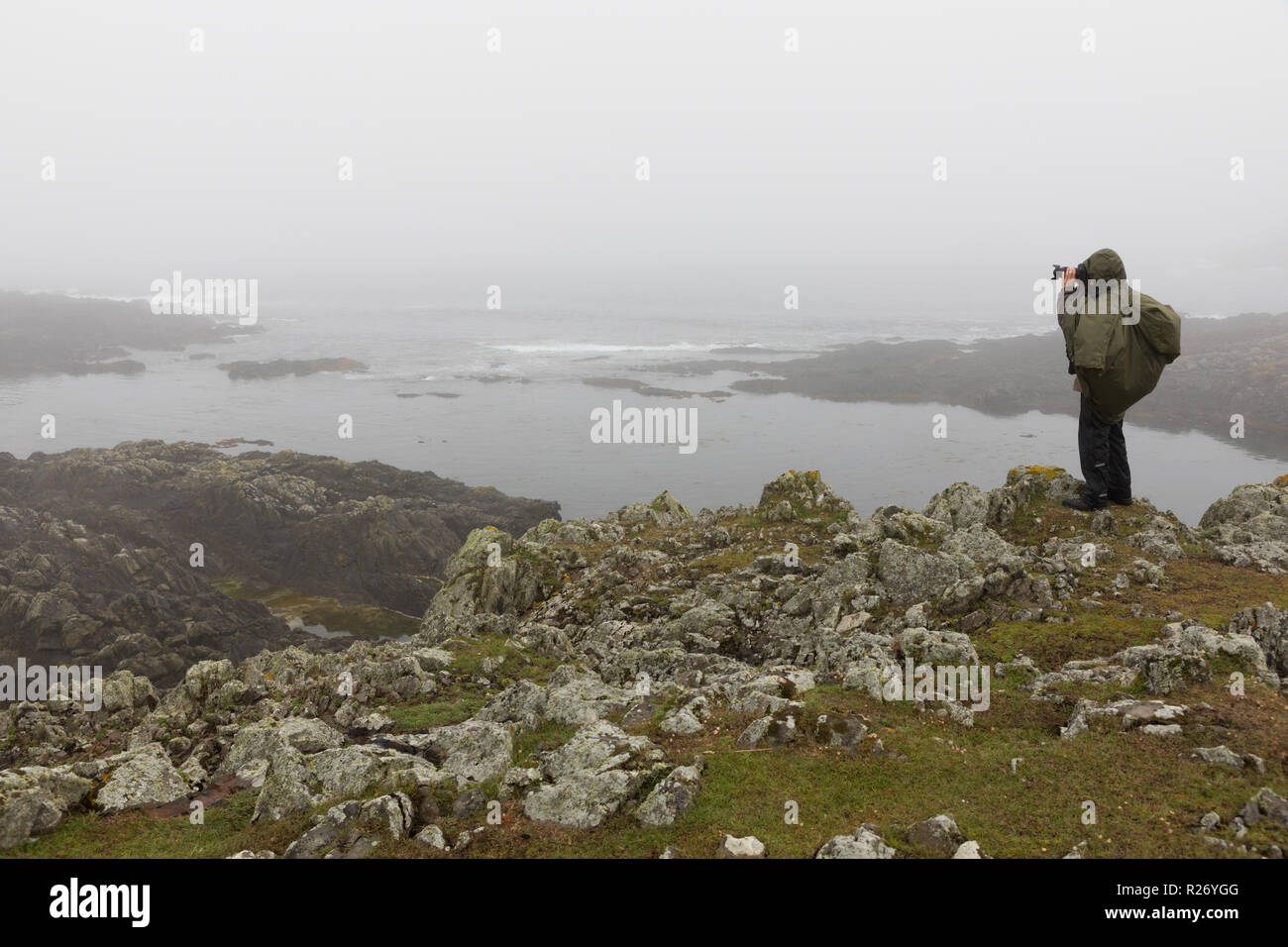 Single photographer taking photo of landscape in the mist, Fair Isle, Shetland Islands Stock Photo
