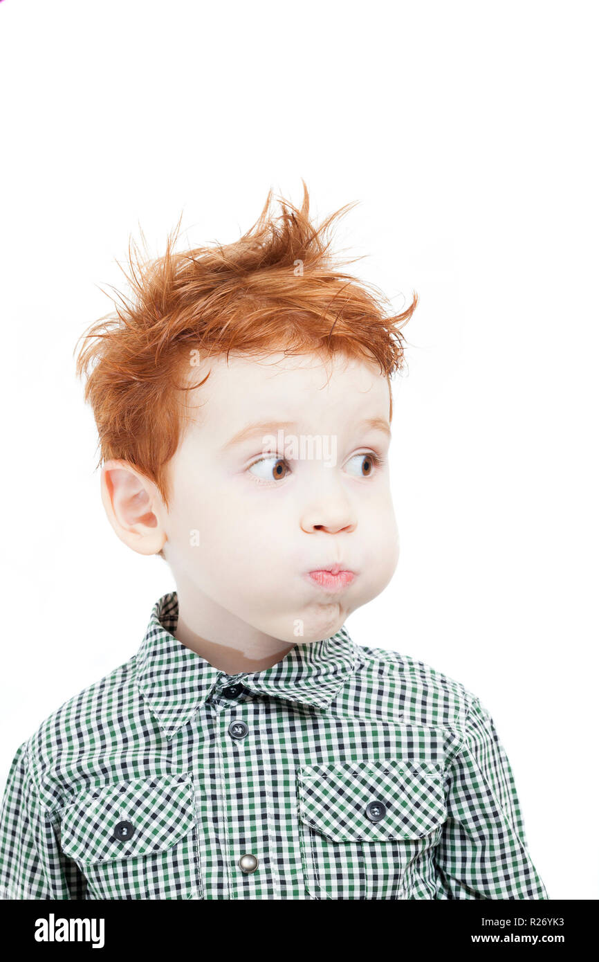 disheveled red hair boy with freckles, looks away and puffed out his air cheeks Stock Photo