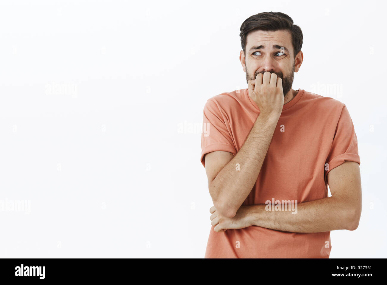Guy freaked out and scared to death, trembling from fear standing insecure  like coward, biting fingernails looking left anxious, panicking, squinting  Stock Photo - Alamy