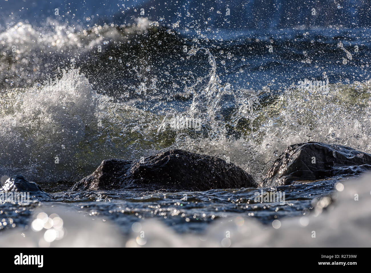 Colorful view with picturesque splashes of water, big waves, stones and ice on the sea in winter Stock Photo