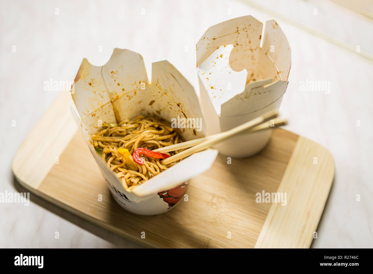 Take away egg noodles on chopsticks in a take away container Stock Photo