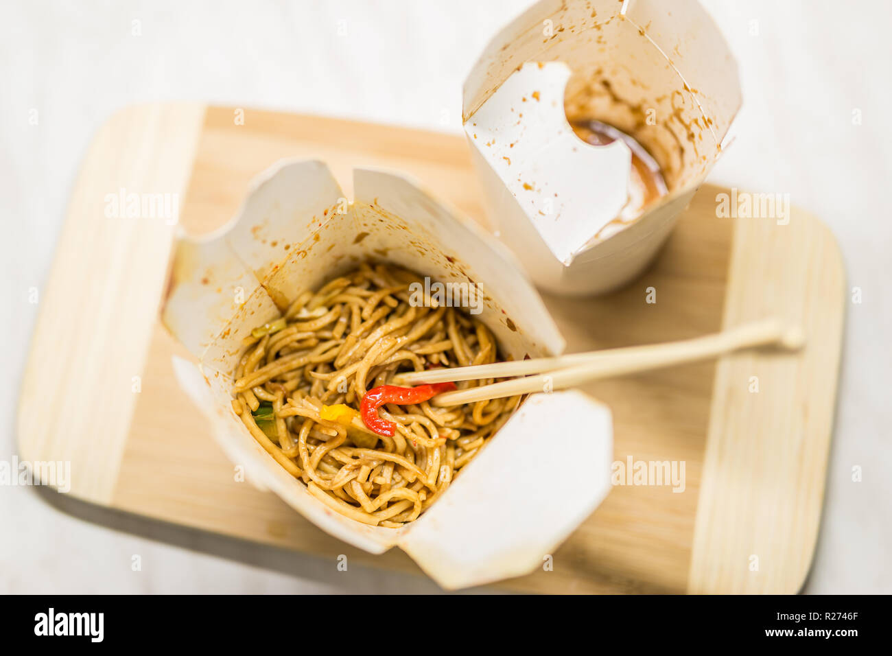 Take away egg noodles on chopsticks in a take away container Stock Photo