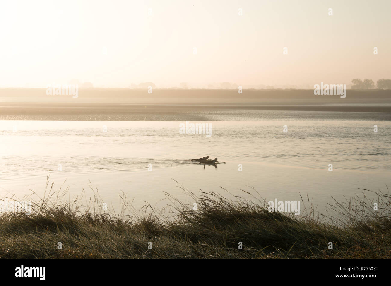 Two silhouetted surfers paddling on the River Severn on a misty sunny early morning Stock Photo