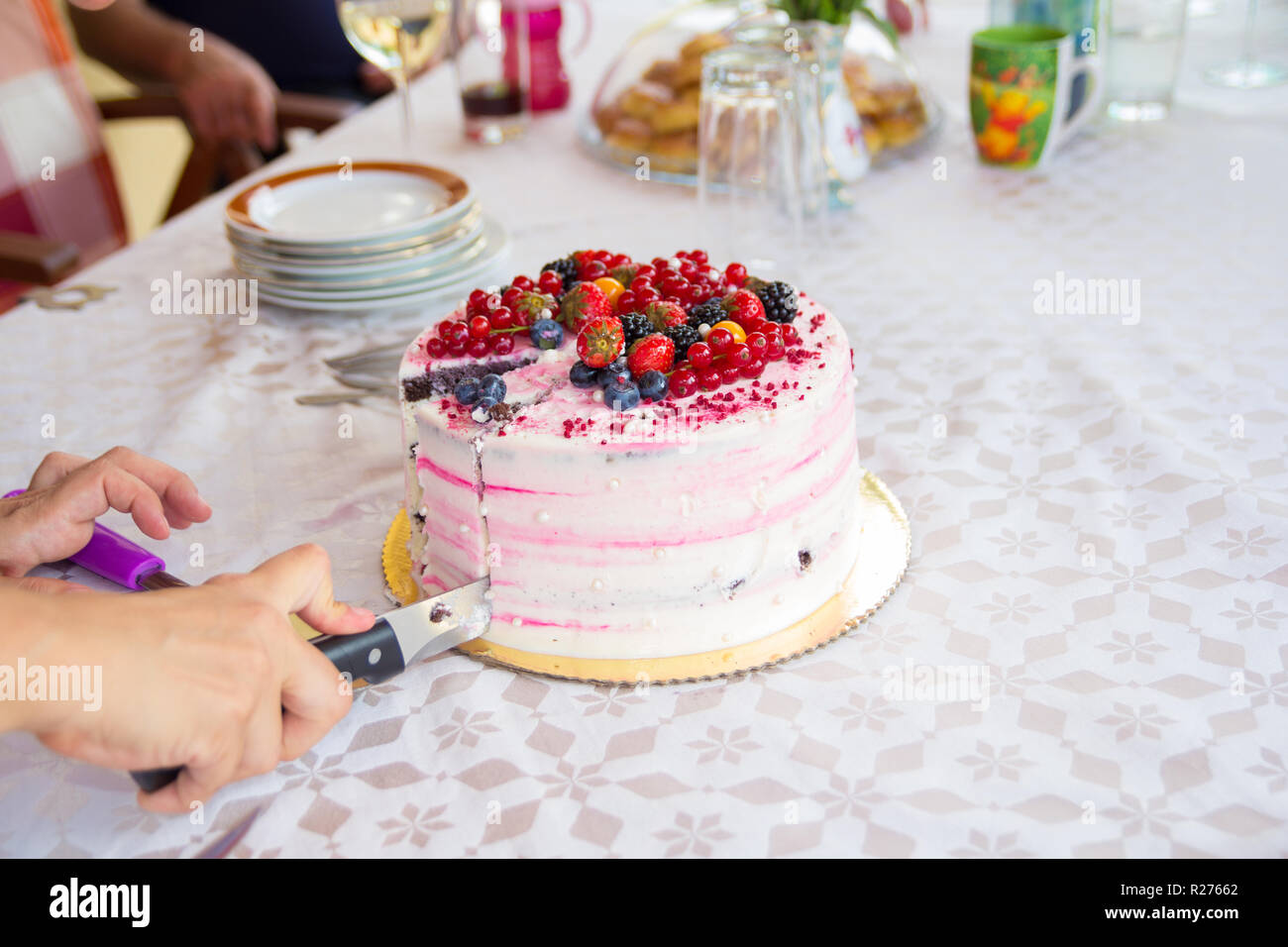 hand with knife slicing birthday cake Stock Photo