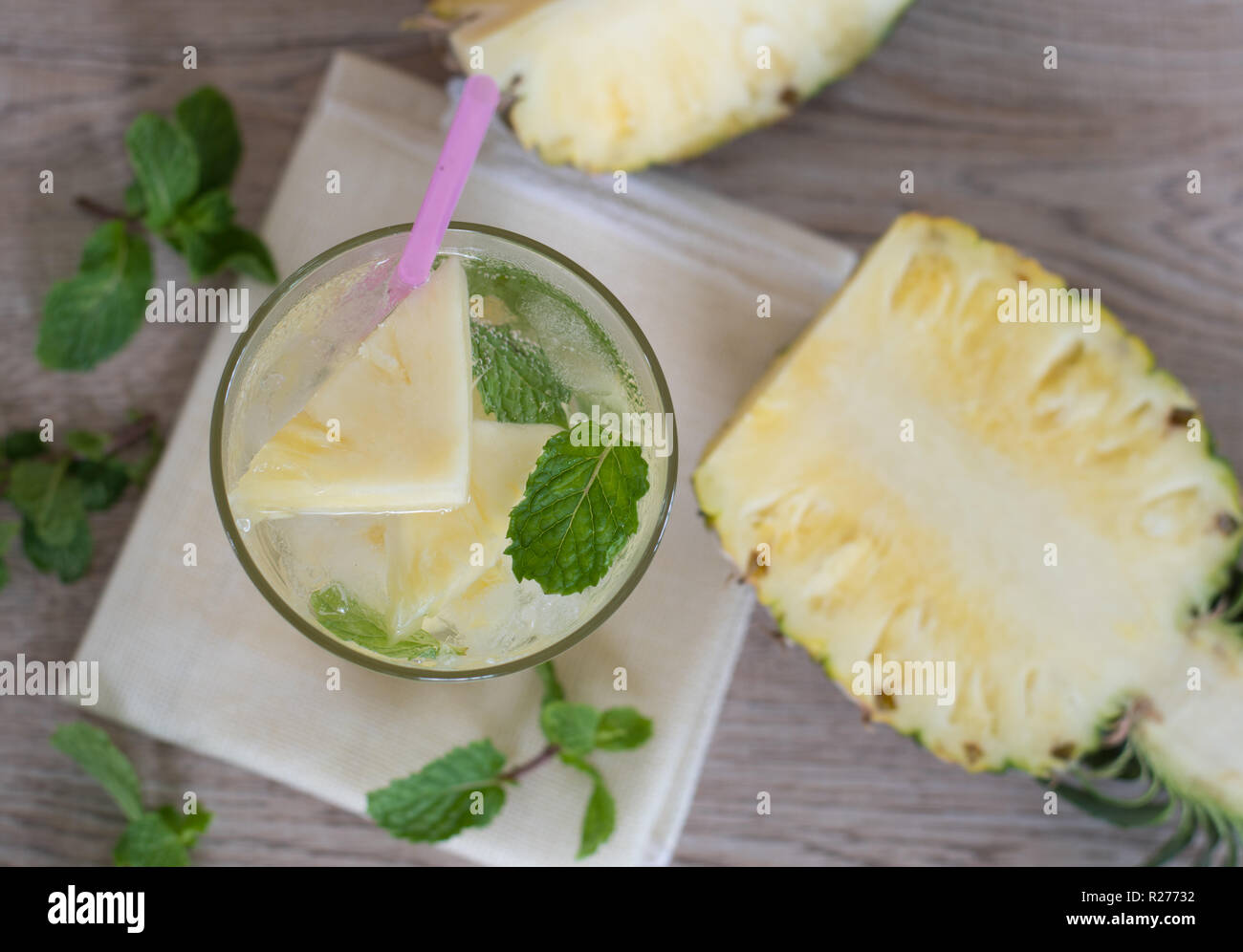 Refreshing pineapple lemonade soda soft drinks or energy drink with ice in a clear tall glass on wooden background Stock Photo
