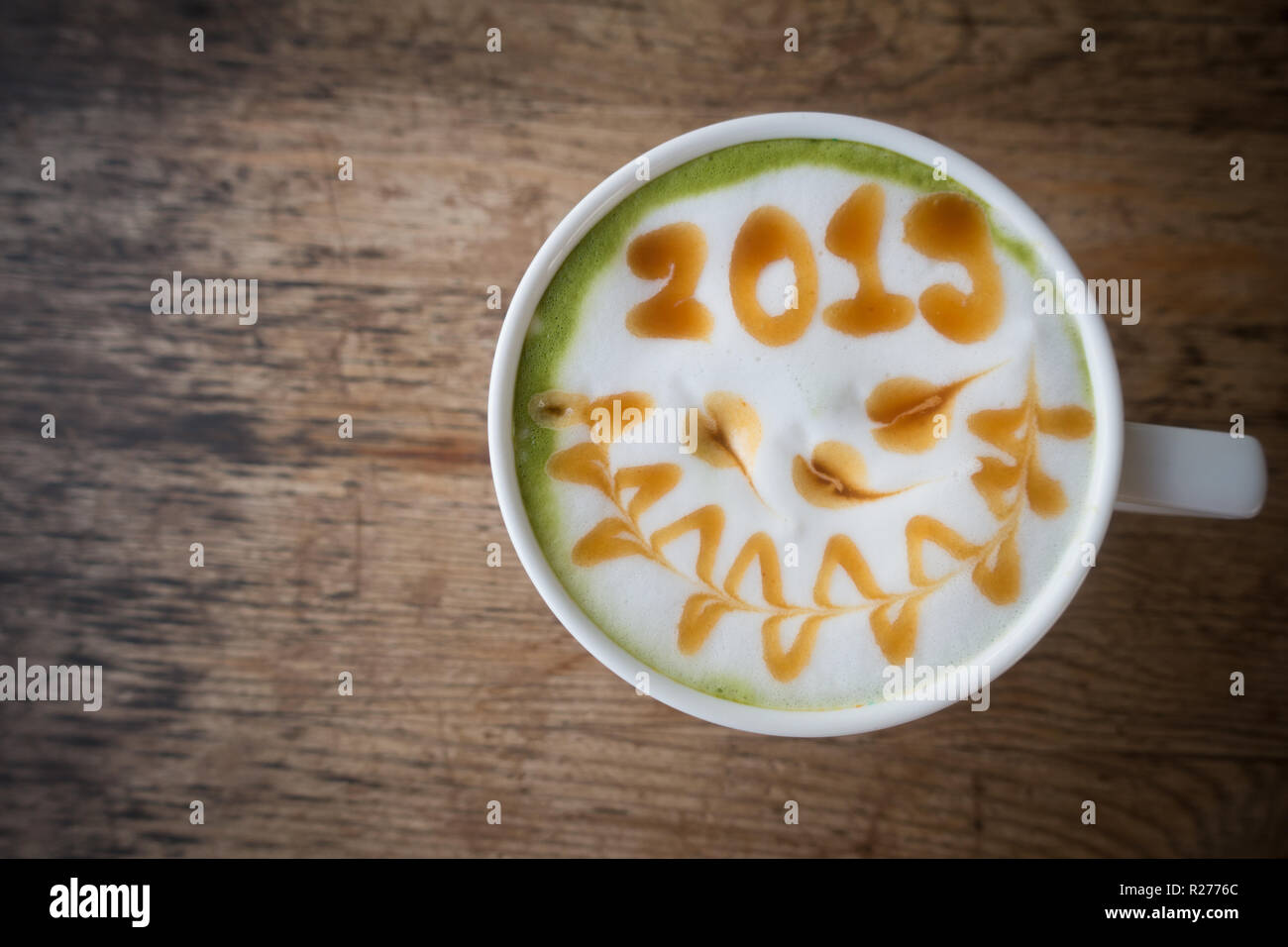 green tea with foam milk art 2019 on wooden table Stock Photo