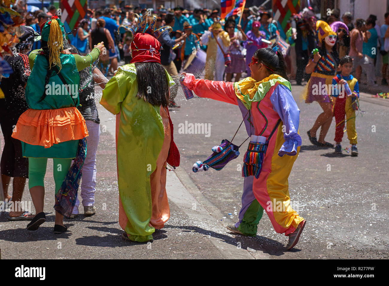 Masked children spraying each other with foam at the annual Carnaval Andino con la Fuerza del Sol in Arica, Chile. Stock Photo