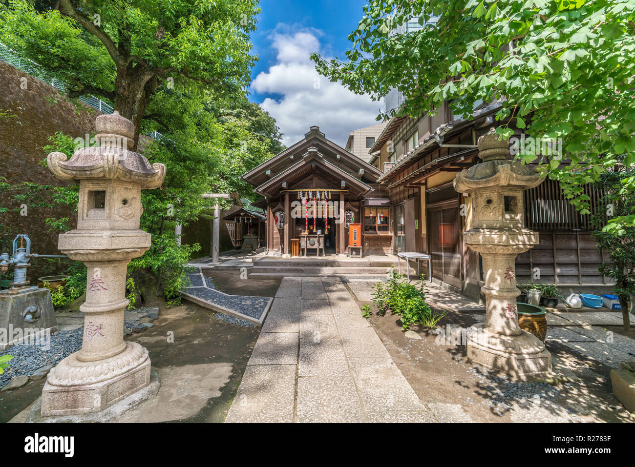 Tokyo, Minato Ward - August 14, 2018 : Ishidoro lanterns and Honden (Main Hall) Hisakuni Jinja Shinto Shrine devoted to Hotei-son god of happiness and Stock Photo