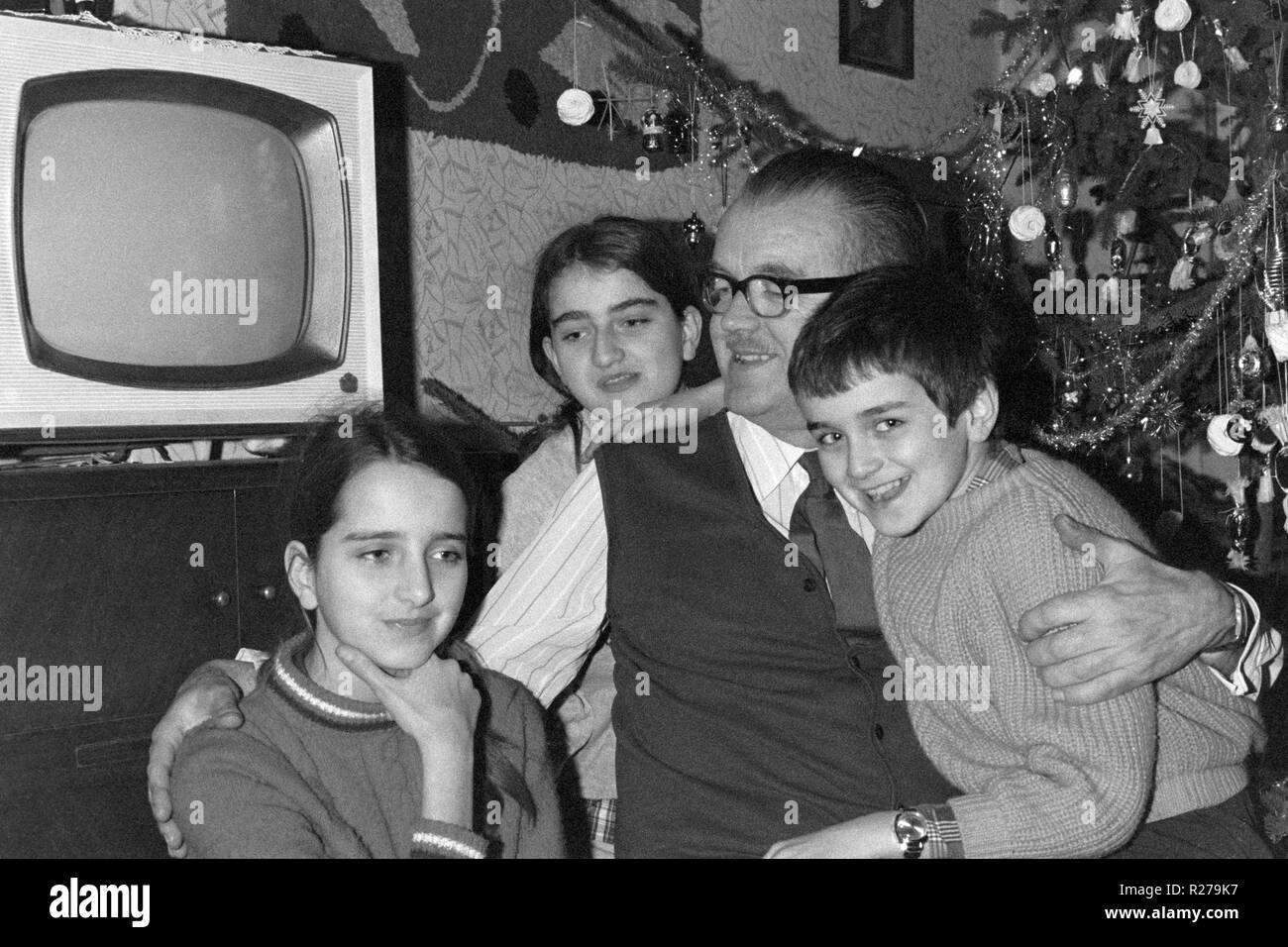 grandfather with grandchildren next to vintage television set at christmas in 1960s hungary Stock Photo