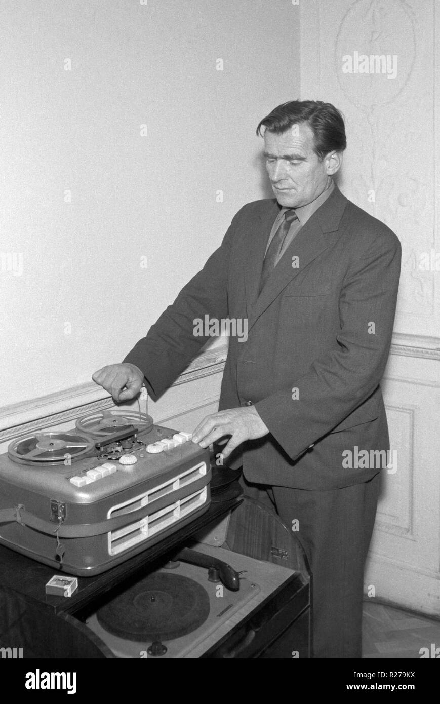 well dressed man using a reel to reel tape recorder alongside a record player 1960s hungary Stock Photo