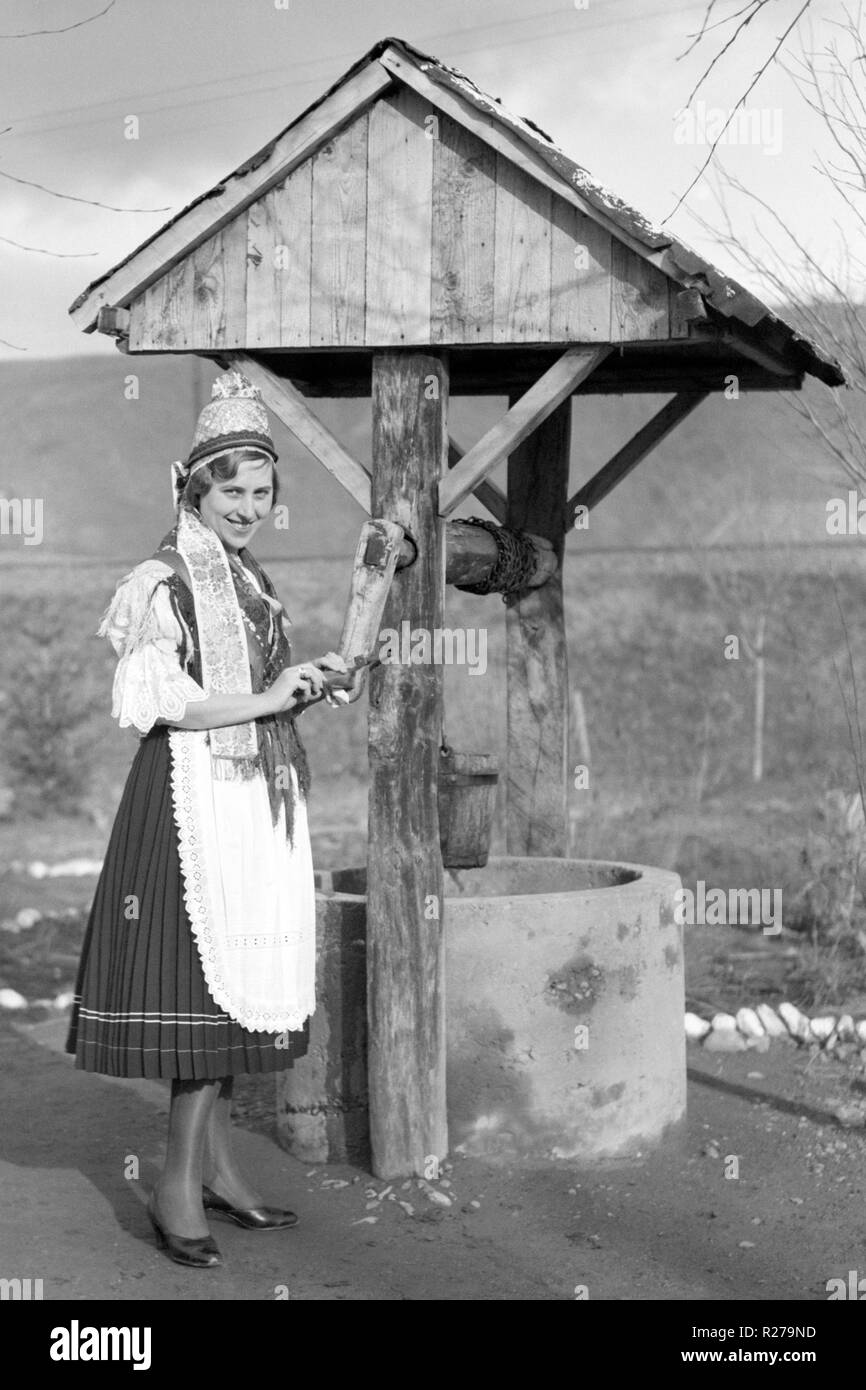 female in hungarian national dress beside a garden well 1930s hungary Stock Photo