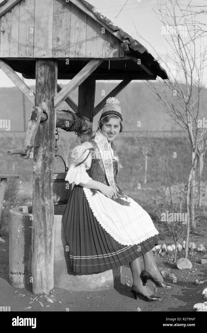 female in hungarian national dress beside a garden well 1930s hungary Stock Photo