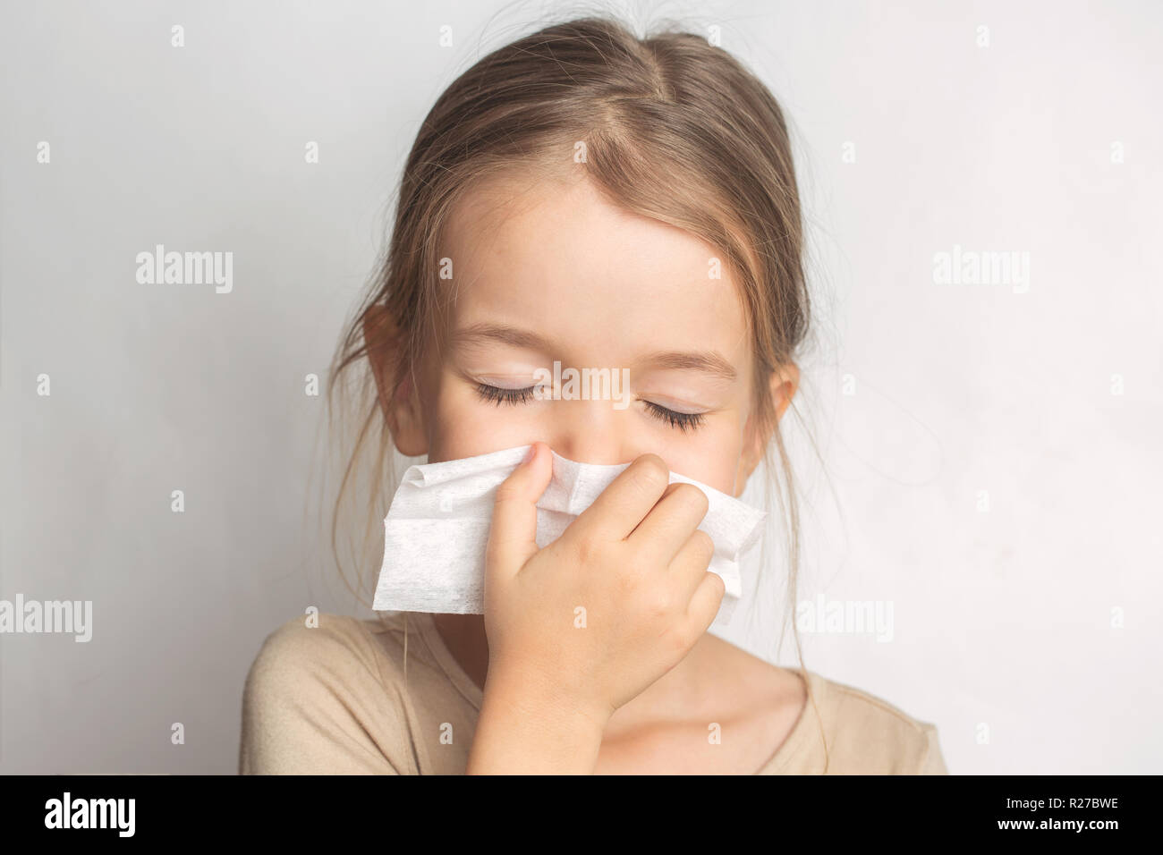 Runny nose in children. A child blows his nose in a handkerchief Stock