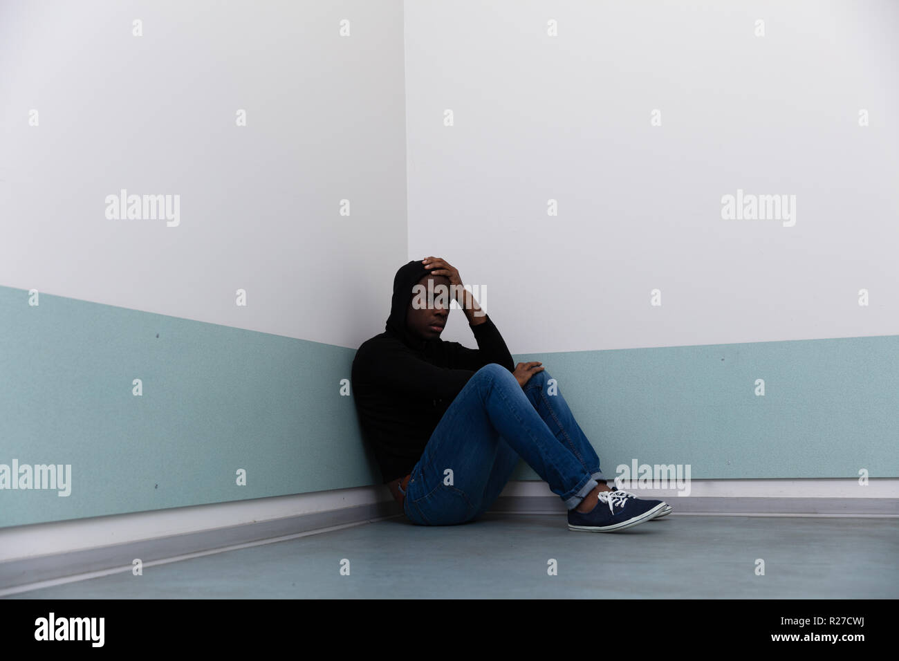 Depressed African Man Sitting Alone On Floor Stock Photo