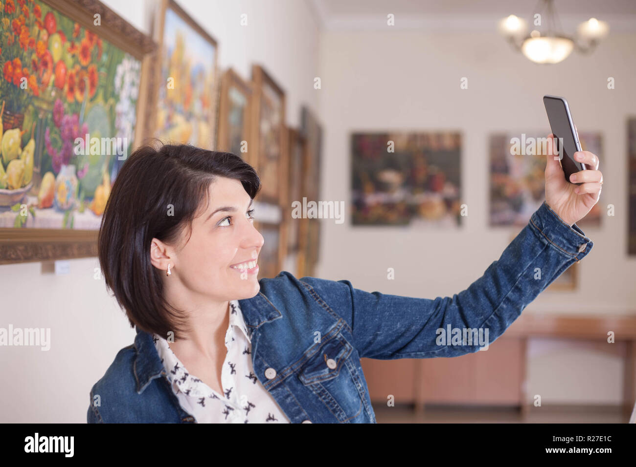 Portrait of a young woman taking a selfie in an art gallery or museum. Stock Photo