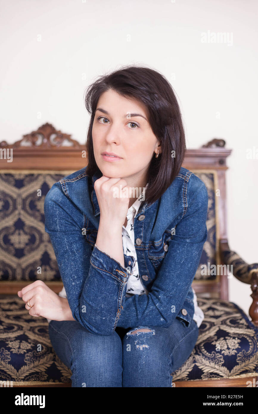 Portrait of a young woman in the interior. Emotions of thoughtfulness and seriousness. Stock Photo