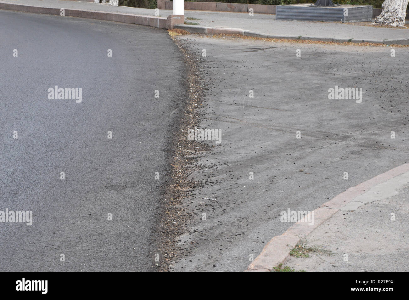 Partly repaired roadway with an edge between the newly laid asphalt concrete and the older area on the right. Stock Photo