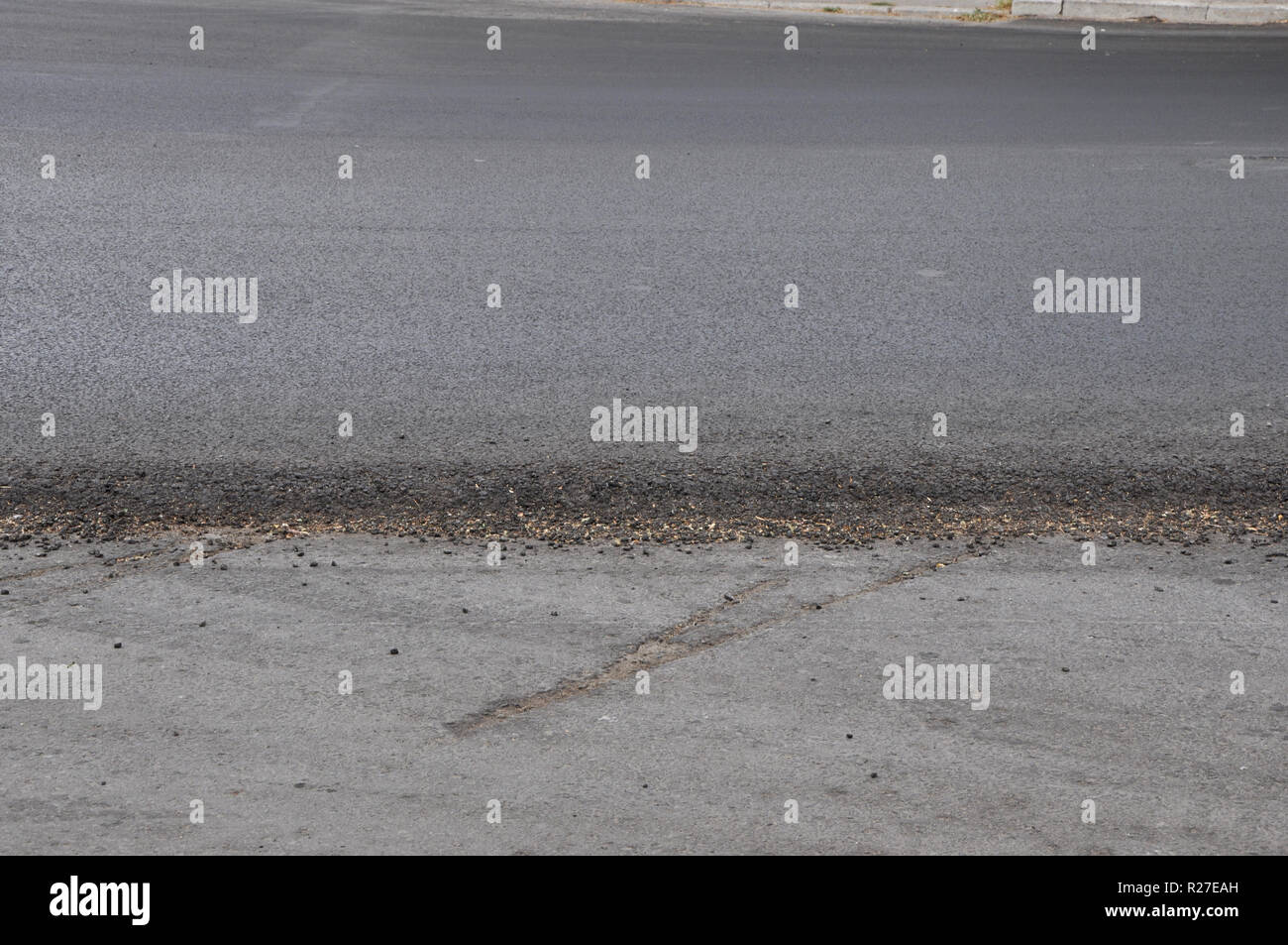 Partly repaired roadway with a horizontal rim between the newly laid asphalt concrete in the upper side and the older area below. Stock Photo