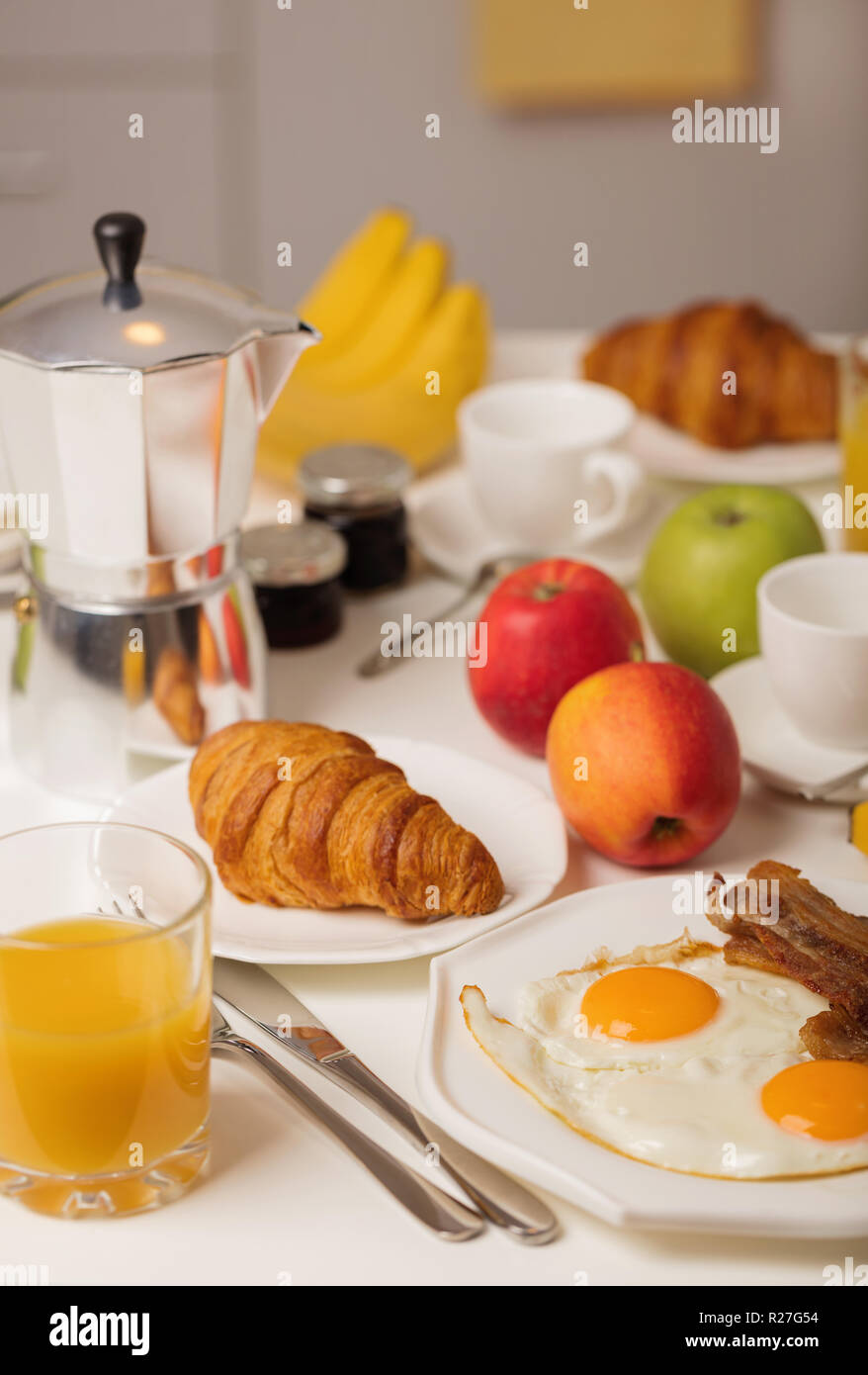 Breakfast time. Fried eggs and bacon. Croissants and orange juice, jam