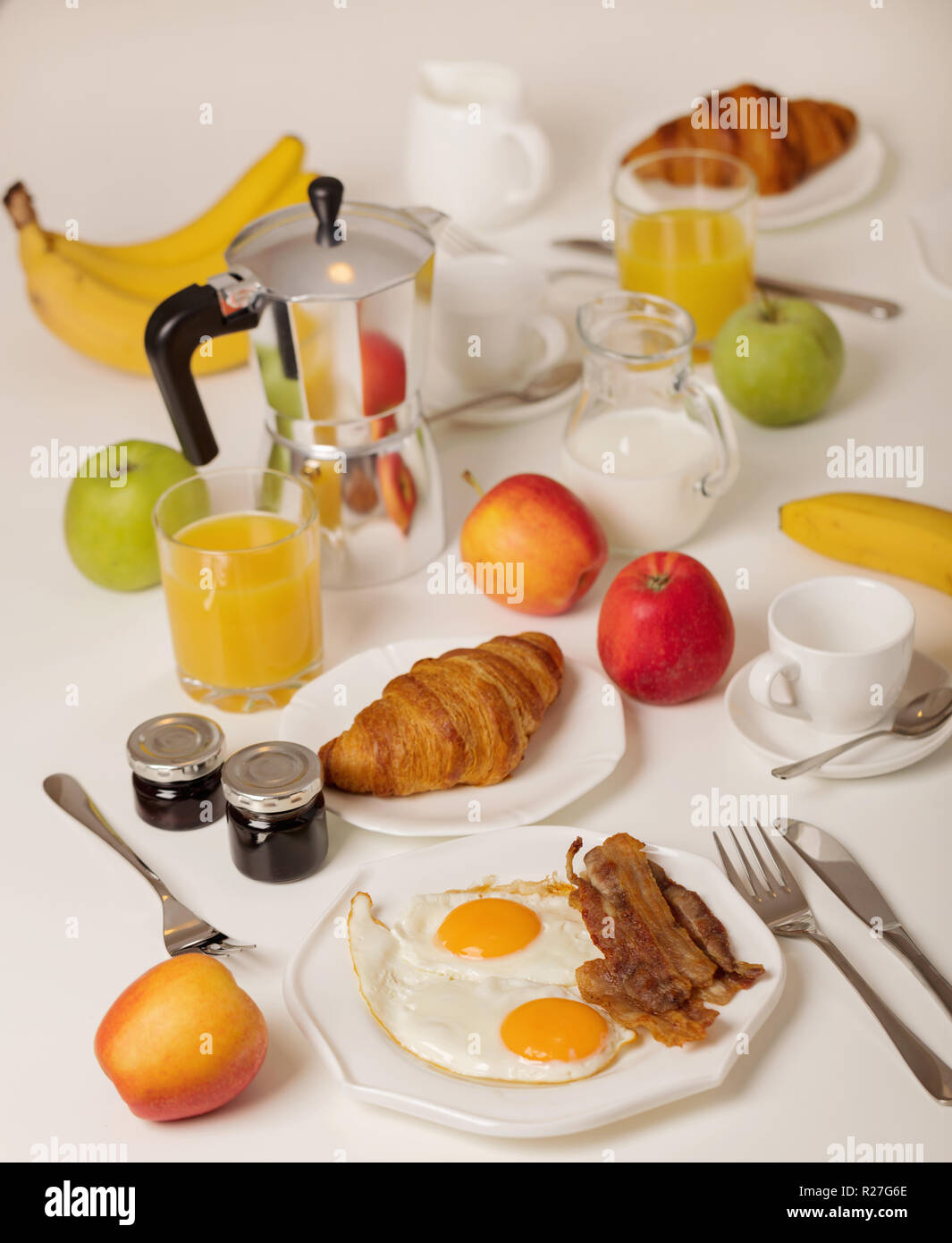 Breakfast time. Fried eggs and bacon. Croissants and orange juice, jam