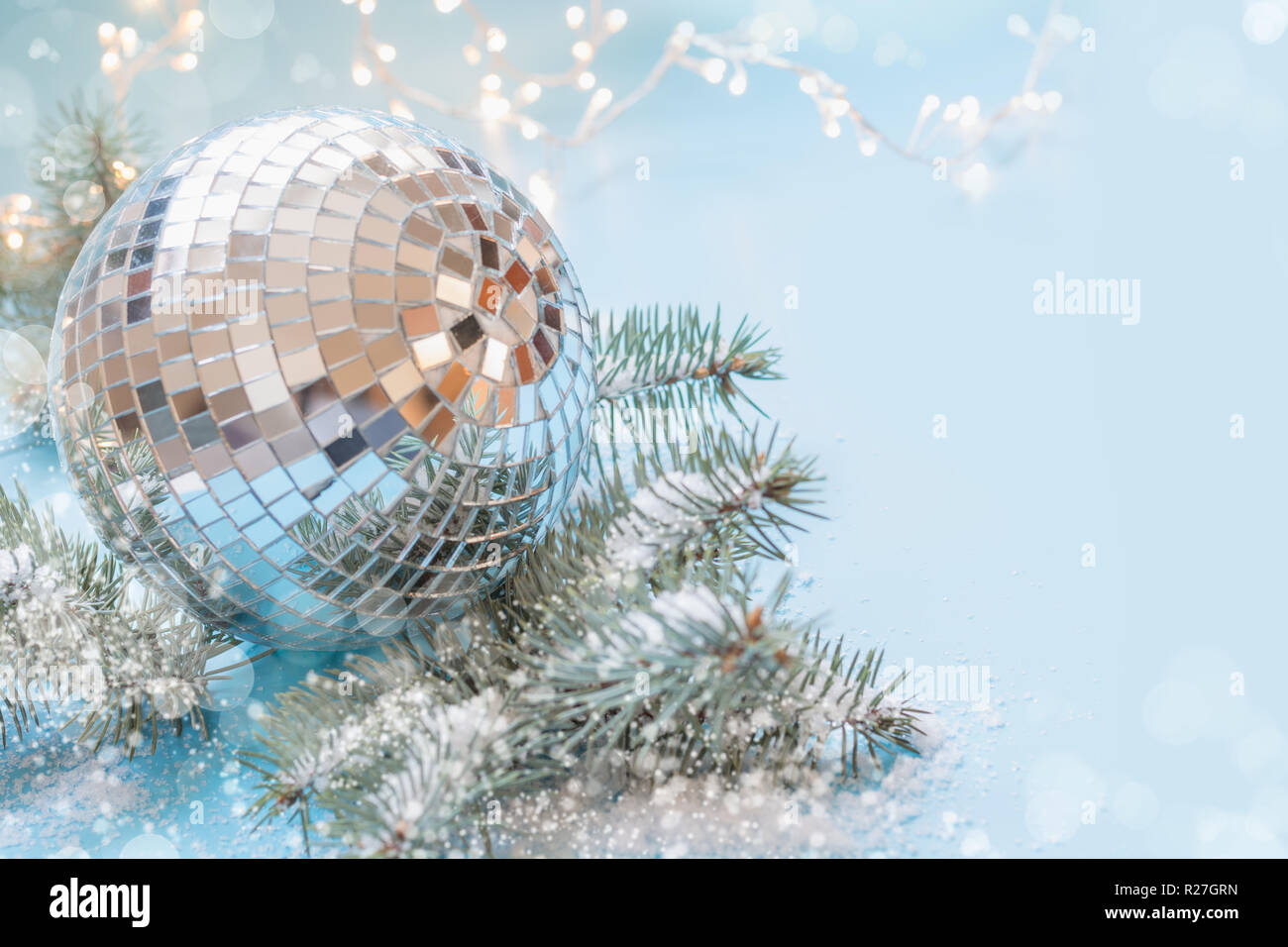 Christmas mirror evening ball with fir tree and garland on pastel blue. Holiday card with copy space. Stock Photo