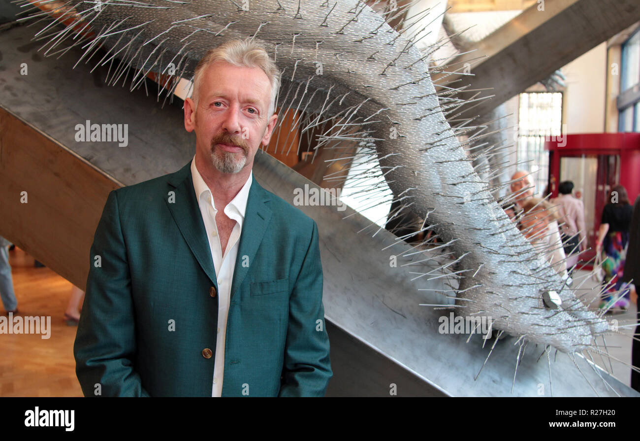 The Scottish artist, David Mach, stands next to one of his huge, coathanger sculptures at the opening of his major exhibition that took place at the City Art Centre in Edinburgh in 2011. Stock Photo