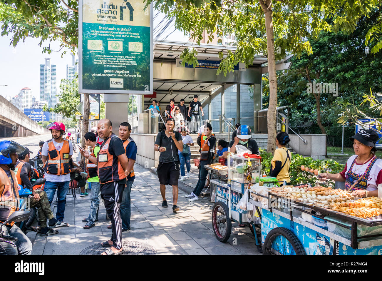 Bangkok, Thailand - 4th October 2018: Motorcycle taxis and street food vendors wait for customers by the entrance to the MRT. The underground system i Stock Photo
