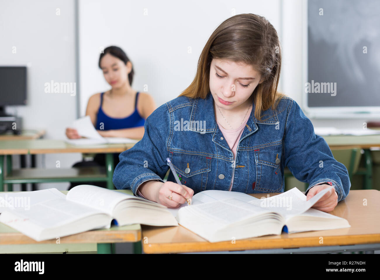 Smiling schoolgirl is learning at the desk in the class Stock Photo - Alamy