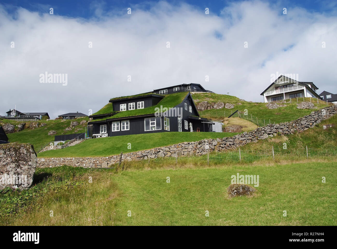 Houses on hilly terrain in Torshavn, Denmark. Eco friendly buildings on natural landscape on cloudy sky. Architecture and design. Ecology and environment. Summer vacation in countryside. Stock Photo