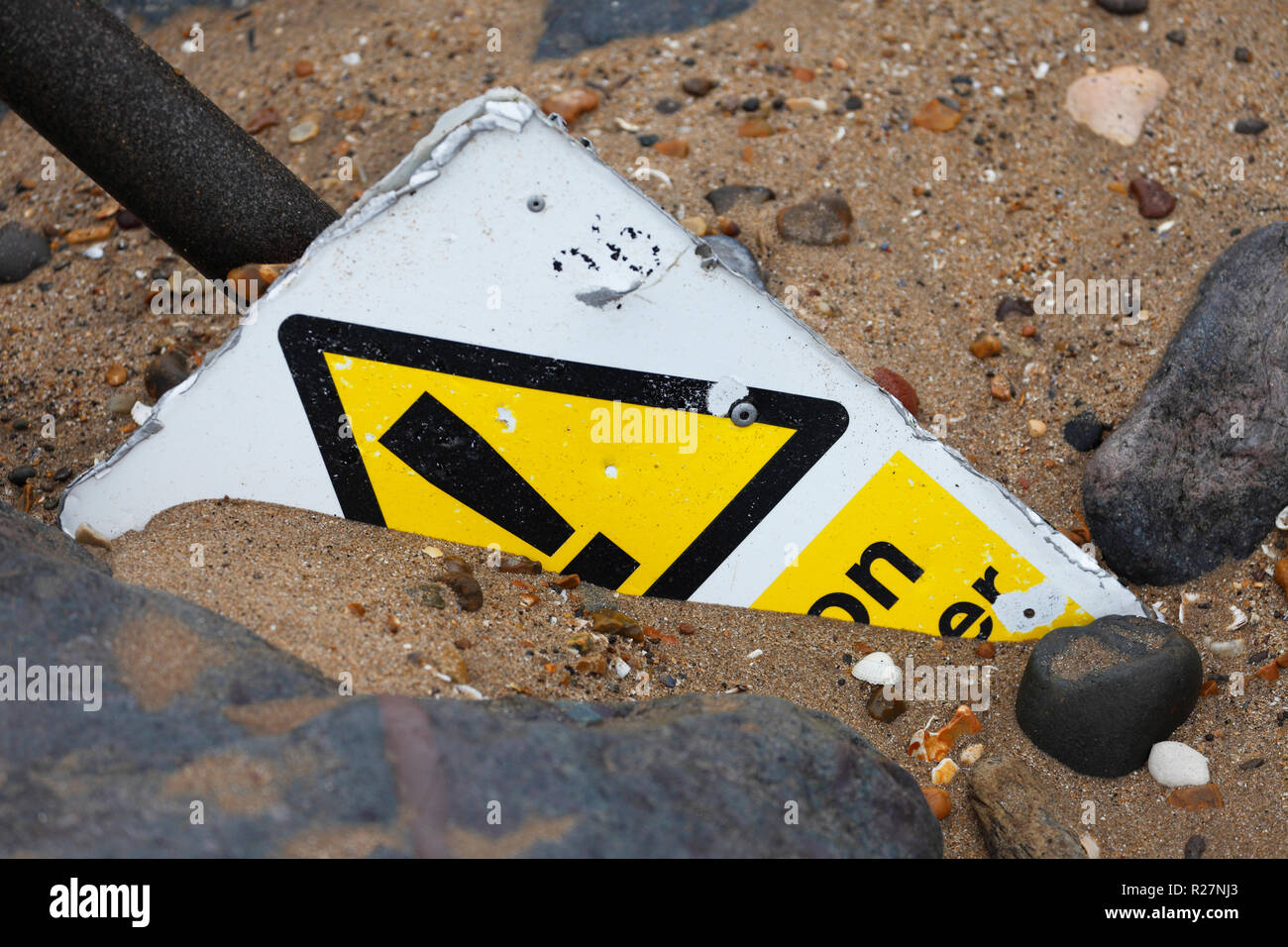 Danger warning sign half buried under sand. Stock Photo
