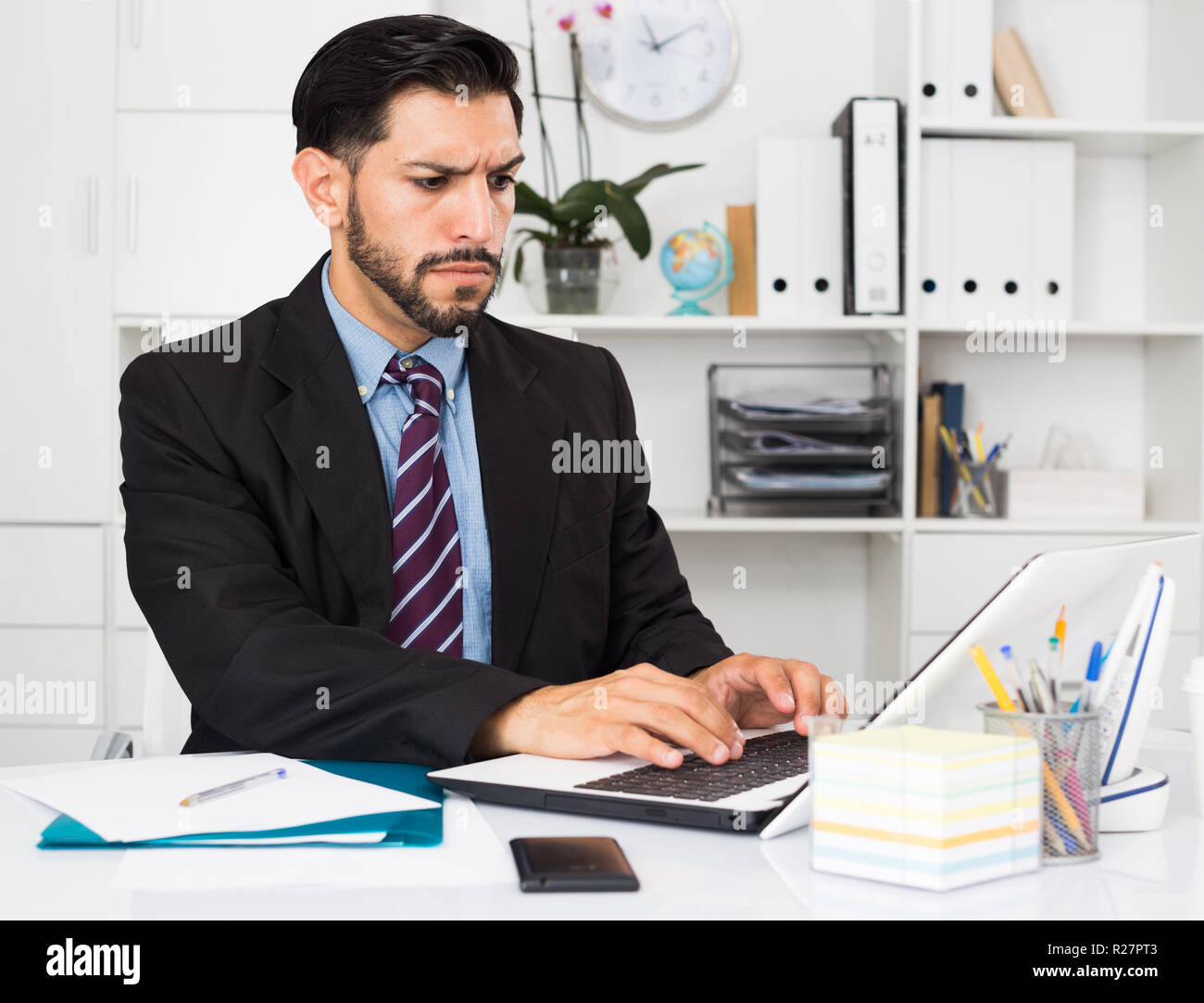 Spanish man is working with documents in laptop in office Stock Photo -  Alamy