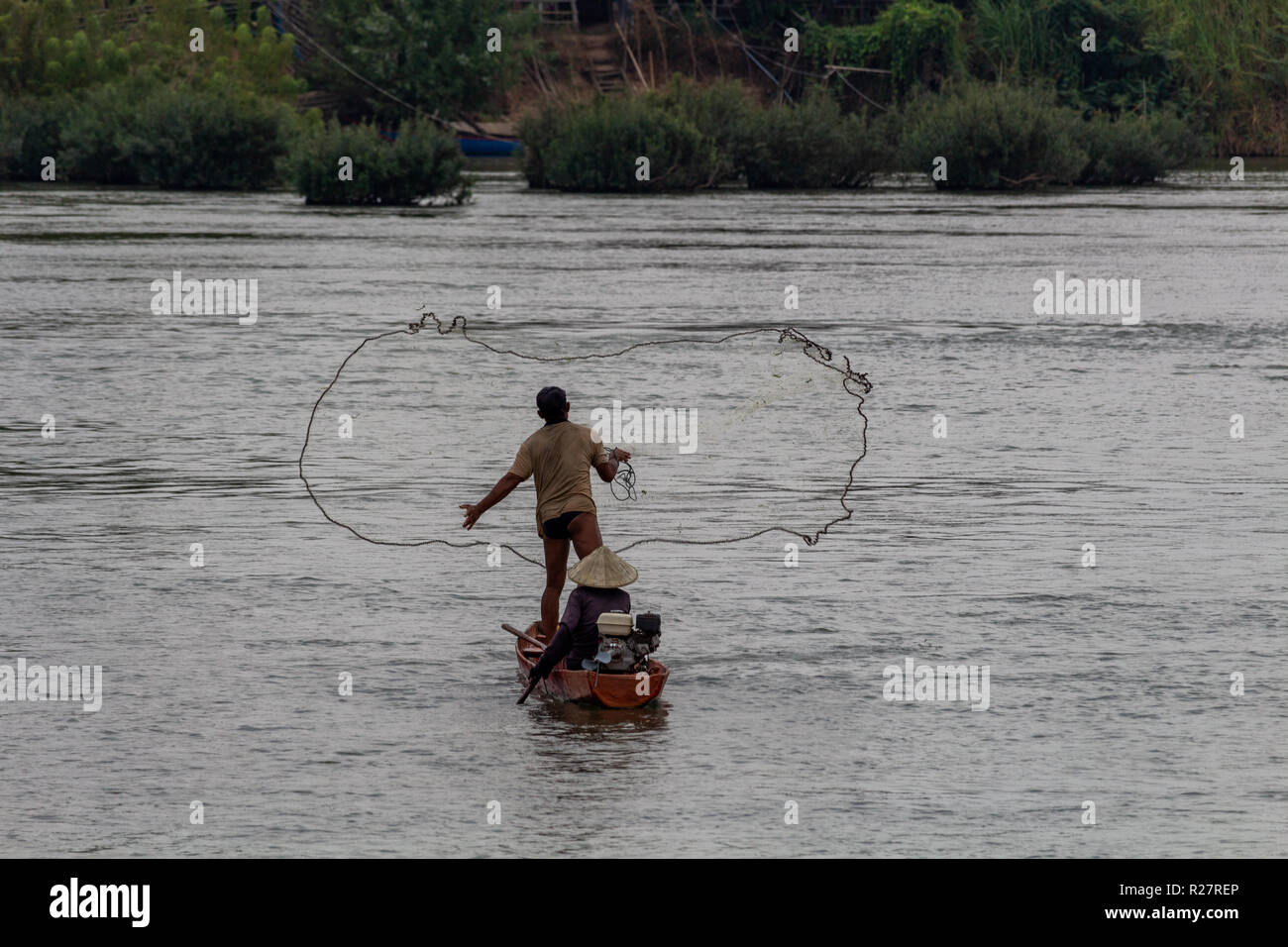 Don Det, Laos - April 24, 2018: Local fisherman throwing a fishing net in the Mekong river at dusk Stock Photo