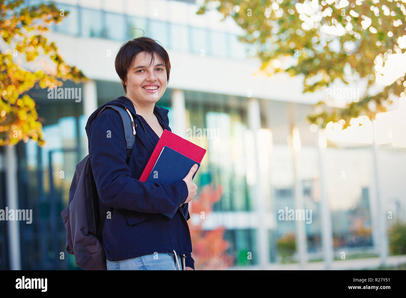 Young woman student holding books, autumn outdoors lifestyle portrait. Stock Photo