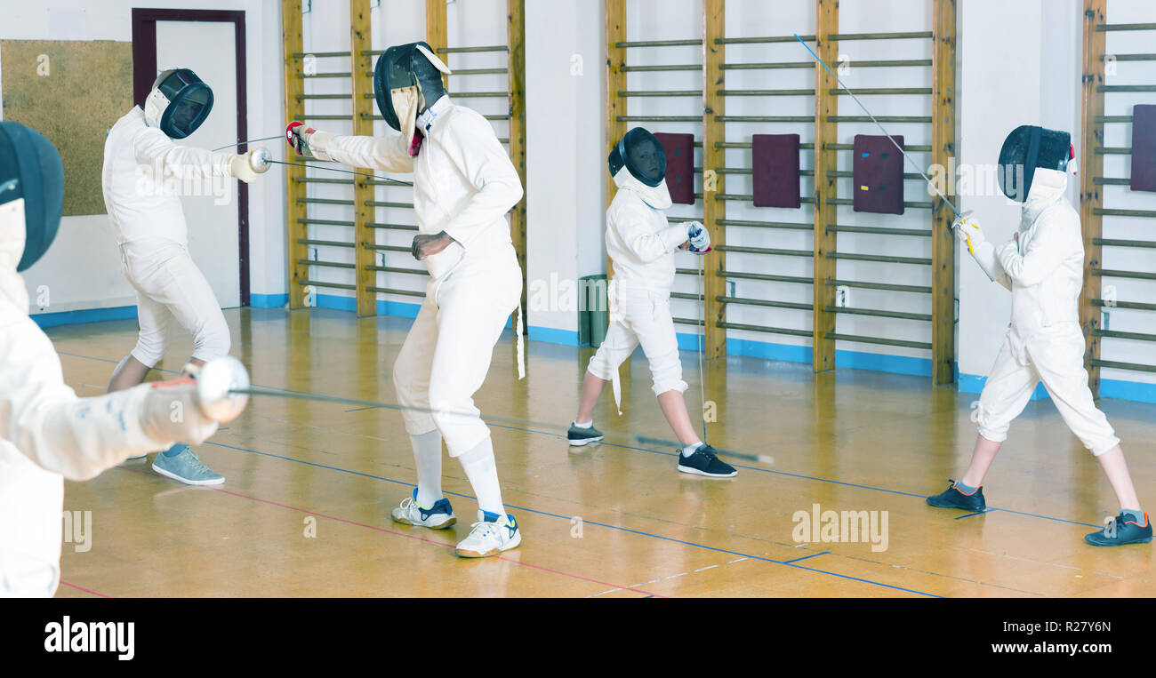 Adults and teens wearing fencing uniform practicing with a foil at a