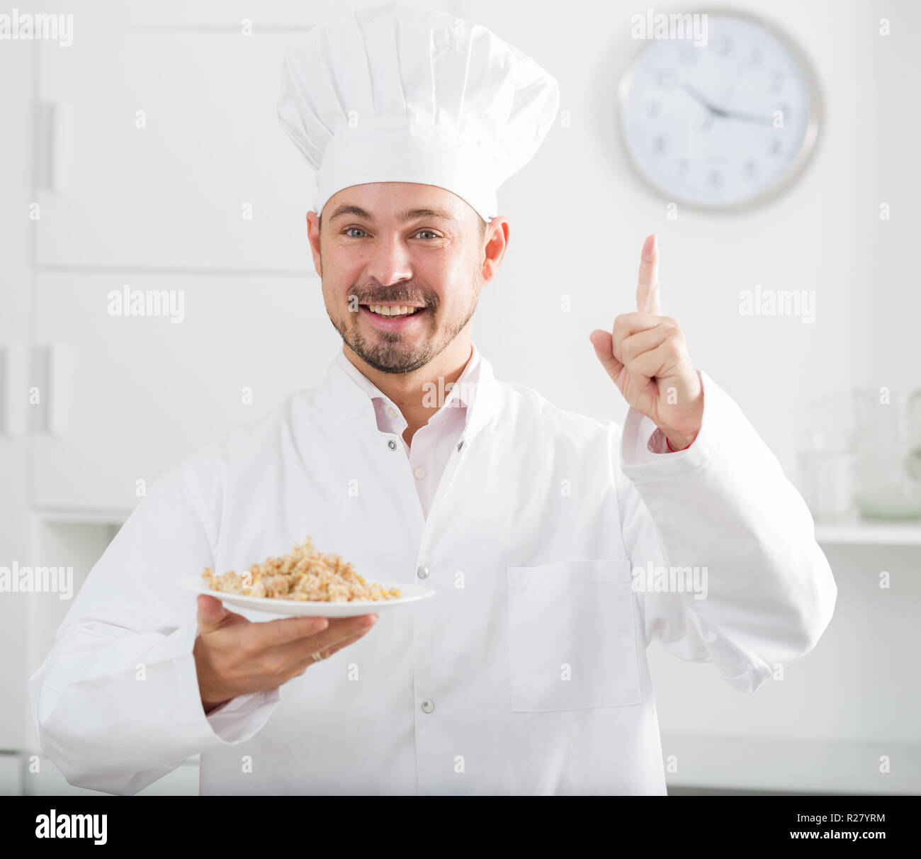 European Cook Young happy european cook in cap offering oat porridge for breakfast ...
