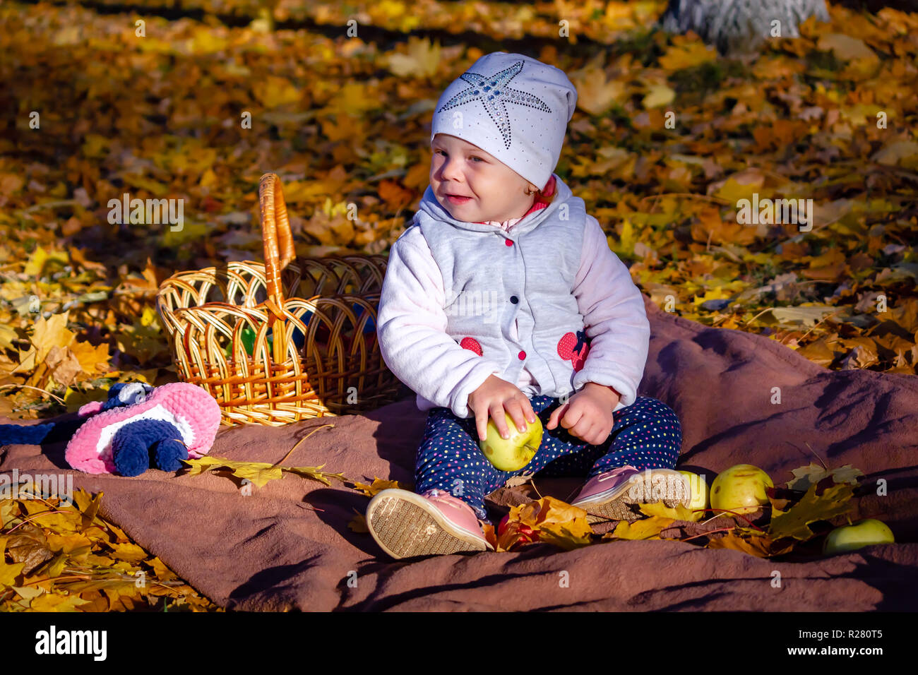 girl in autumn eating an apple sitting on yellow Stock Photo