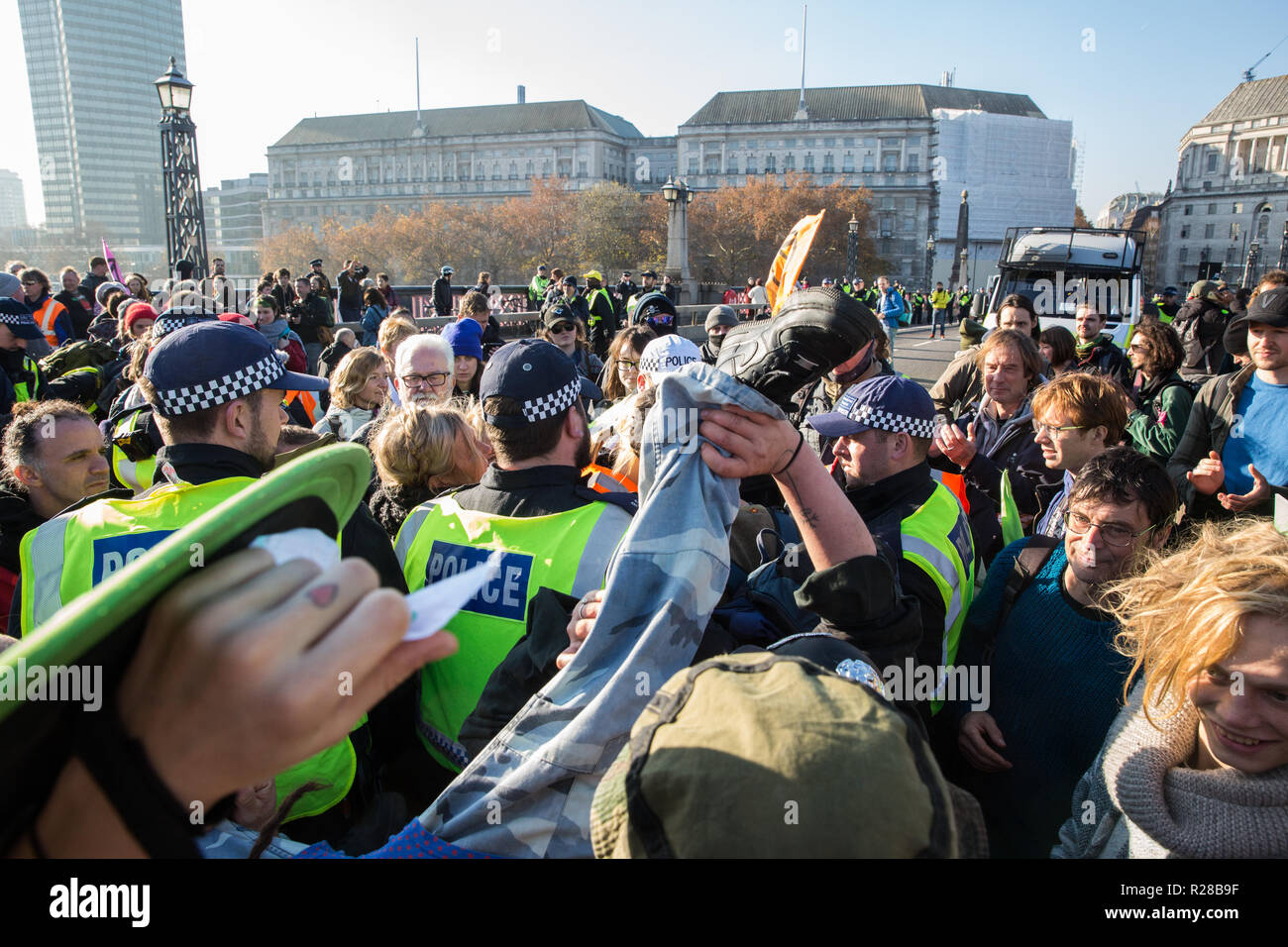 London, UK. 17th November, 2018. Police officers arrest a man after environmental campaigners from Extinction Rebellion blocked Lambeth Bridge, one of five bridges blocked in central London, as part of a Rebellion Day event to highlight 'criminal inaction in the face of climate change catastrophe and ecological collapse' by the UK Government as part of a programme of civil disobedience during which scores of campaigners have been arrested. Clowns from Clandestine Insurgent Rebel Clown Army (CIRCA follow them. Credit: Mark Kerrison/Alamy Live News Stock Photo