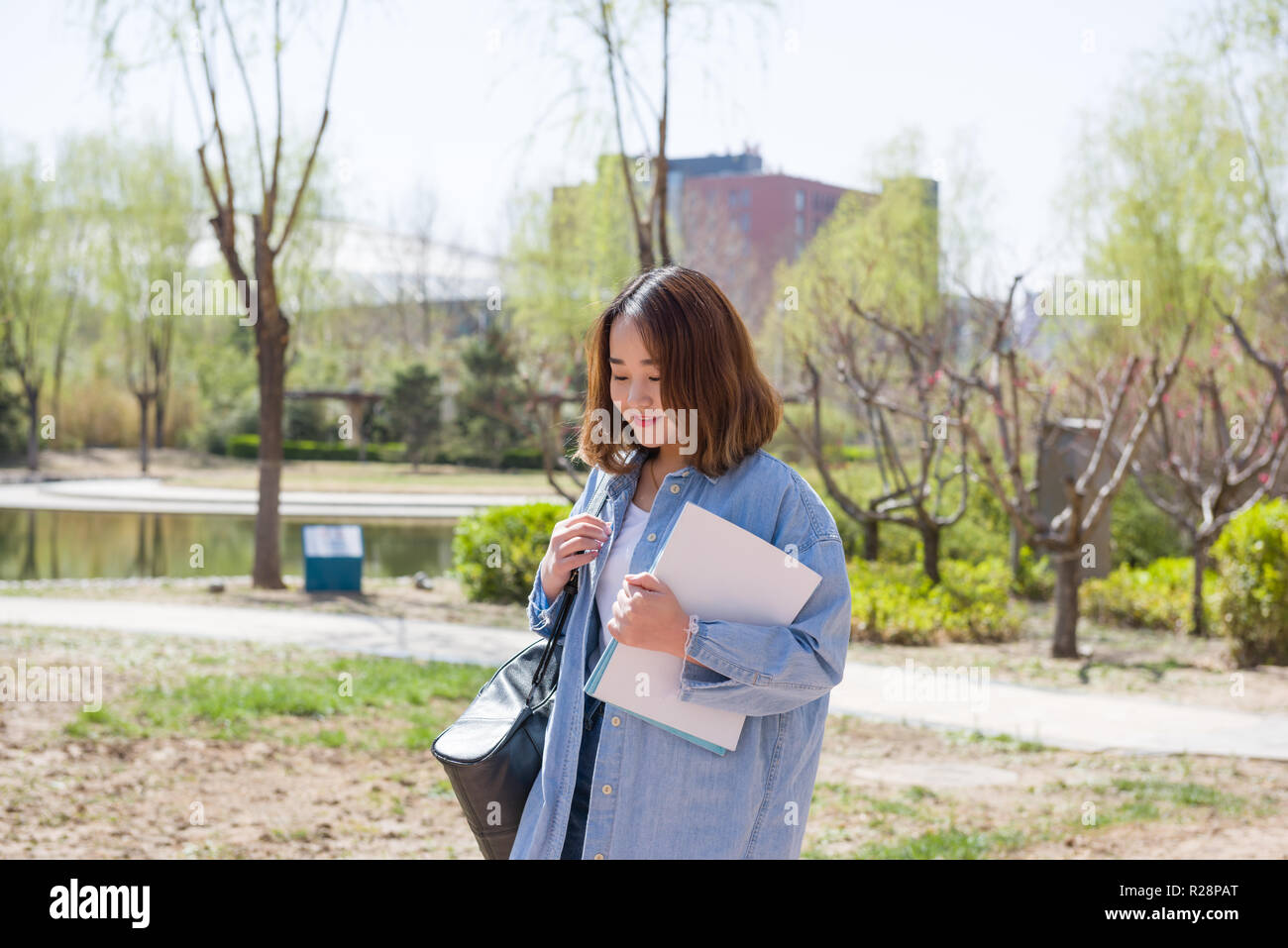A beautiful college student carrying books at the campus. Female ...