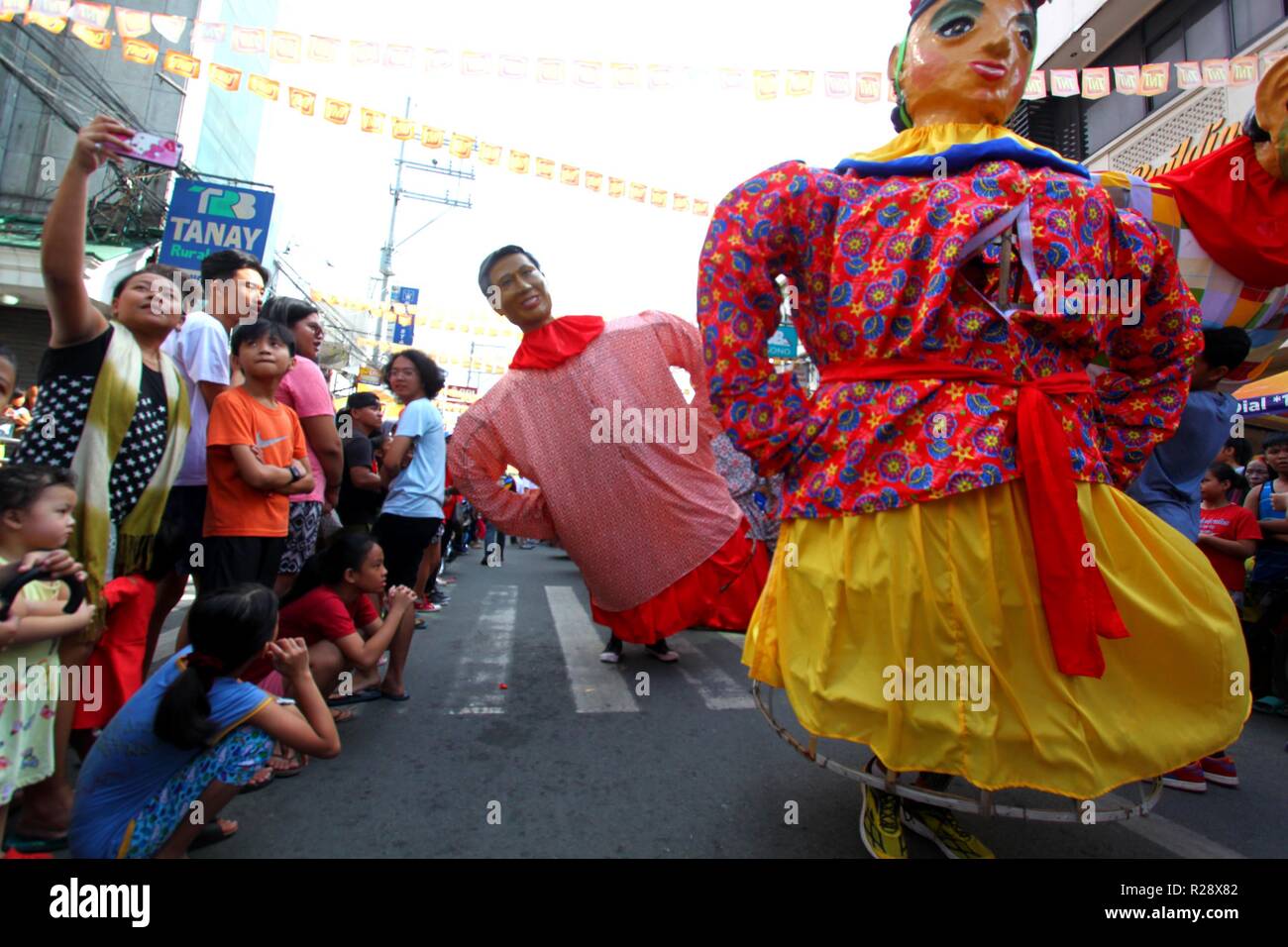 Tourist taking selfie picture during the Higantes (Giant) effigy marches on the streets town of Angono province of Rizal on November 18, 2018. Higantes (Giant) Festival is celebrated November in the city of Angono, Province of Rizal in the Philippines to honor San Clemente, the patron saint of fishermen. The festival features a parade of hundreds of higantes, papier-mâché giants. Higantes (Giant) are puppets rendered as man or woman in various costumes; their face gives a commanding look, their hands on the waist. (Photo by Gregorio B. Dantes Jr./Pacific Press) Stock Photo
