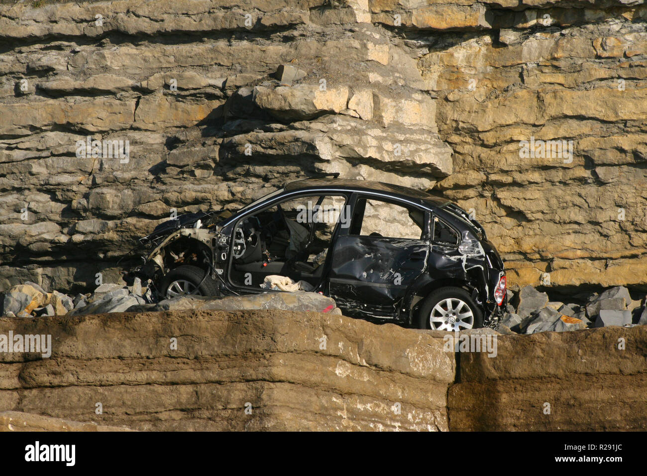 A VW Volkswagen car that has gone over the cliff at Nash Point Beach in the Vale of Glamorgan, South Wales, UK Stock Photo