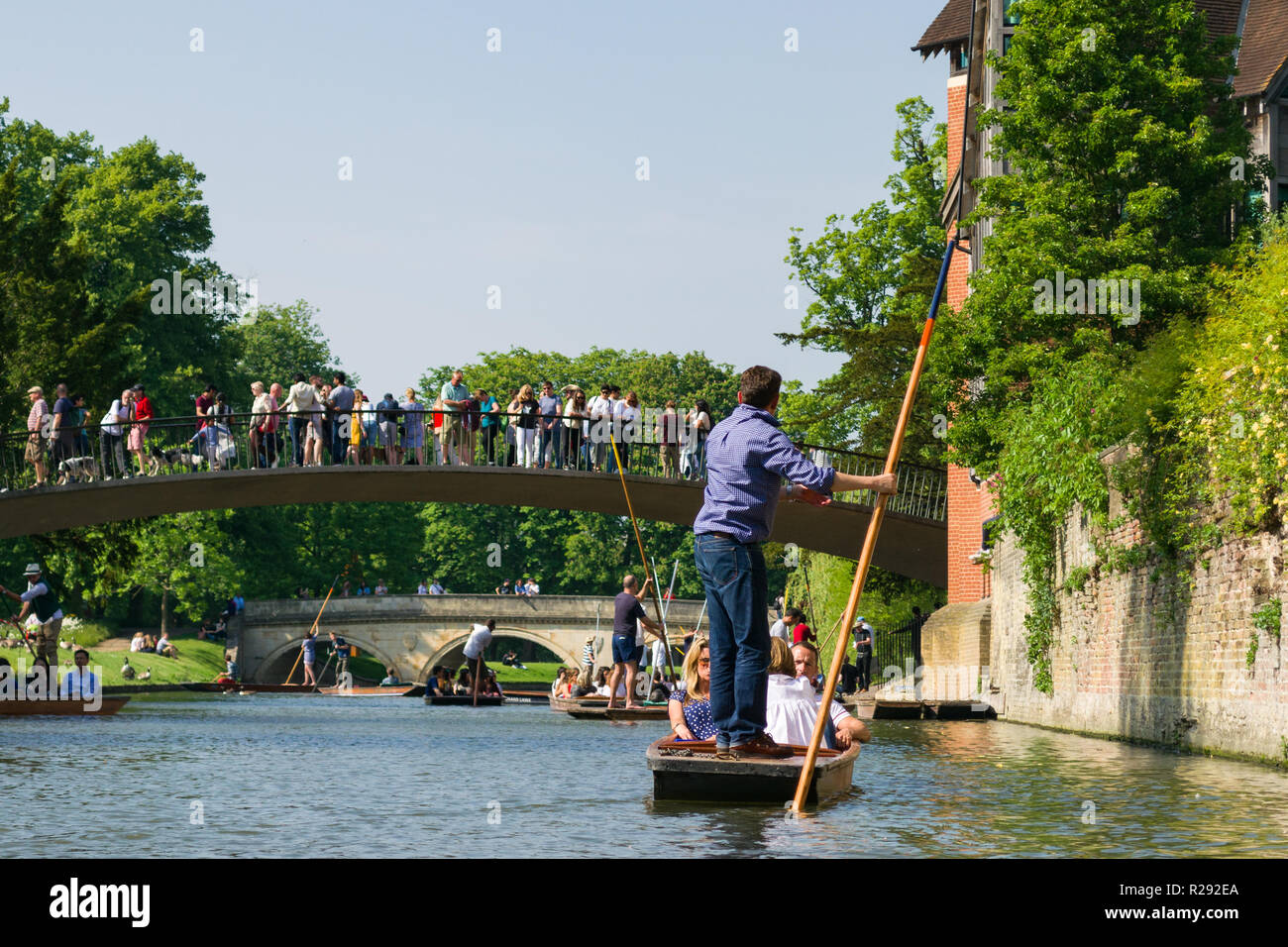 Several punt boats on a busy stretch of the river Cam with tourists standing on Garret Hostel Bridge, Cambridge, UK Stock Photo